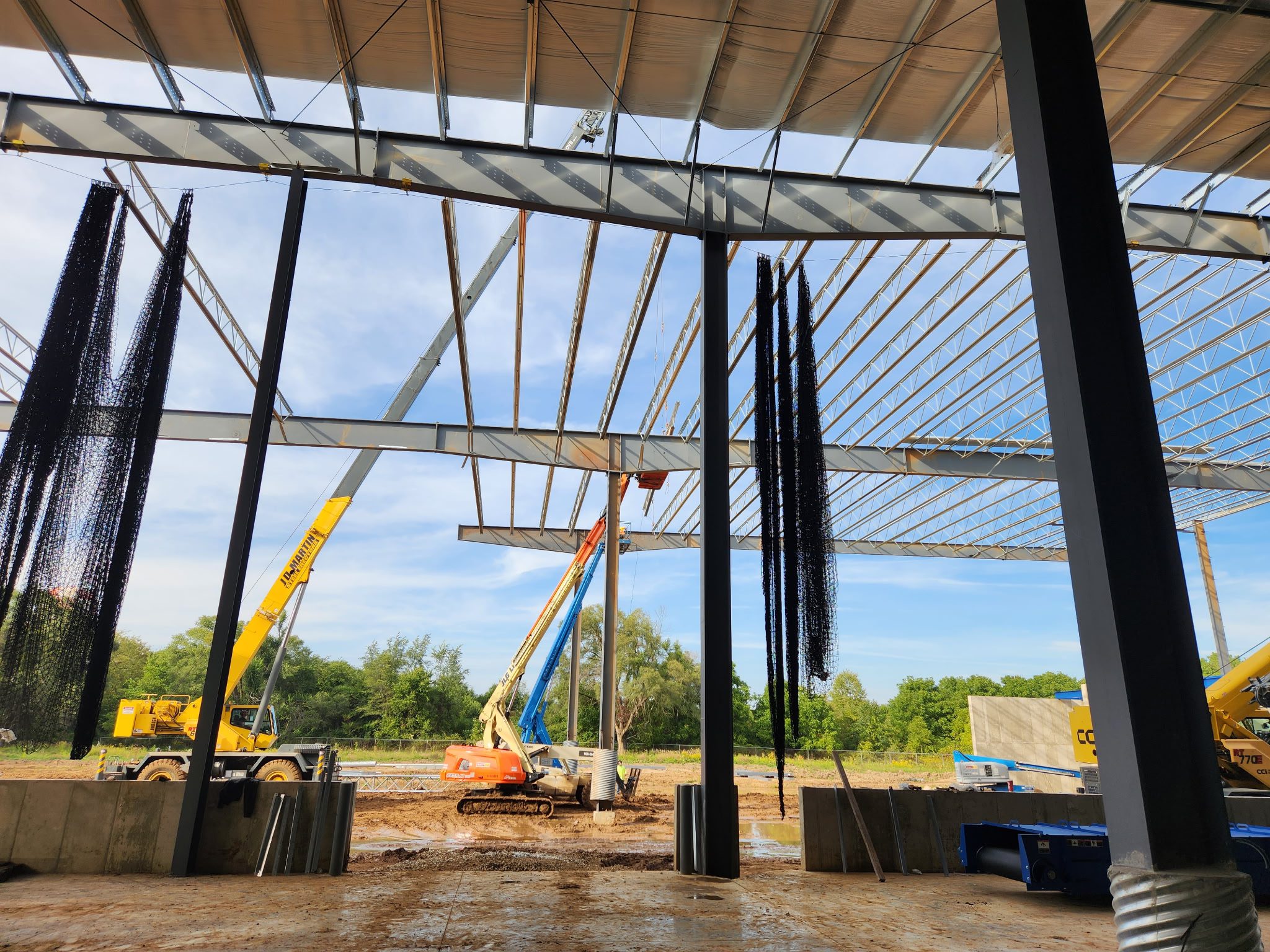 Construction site with cranes and steel framework under a clear sky.