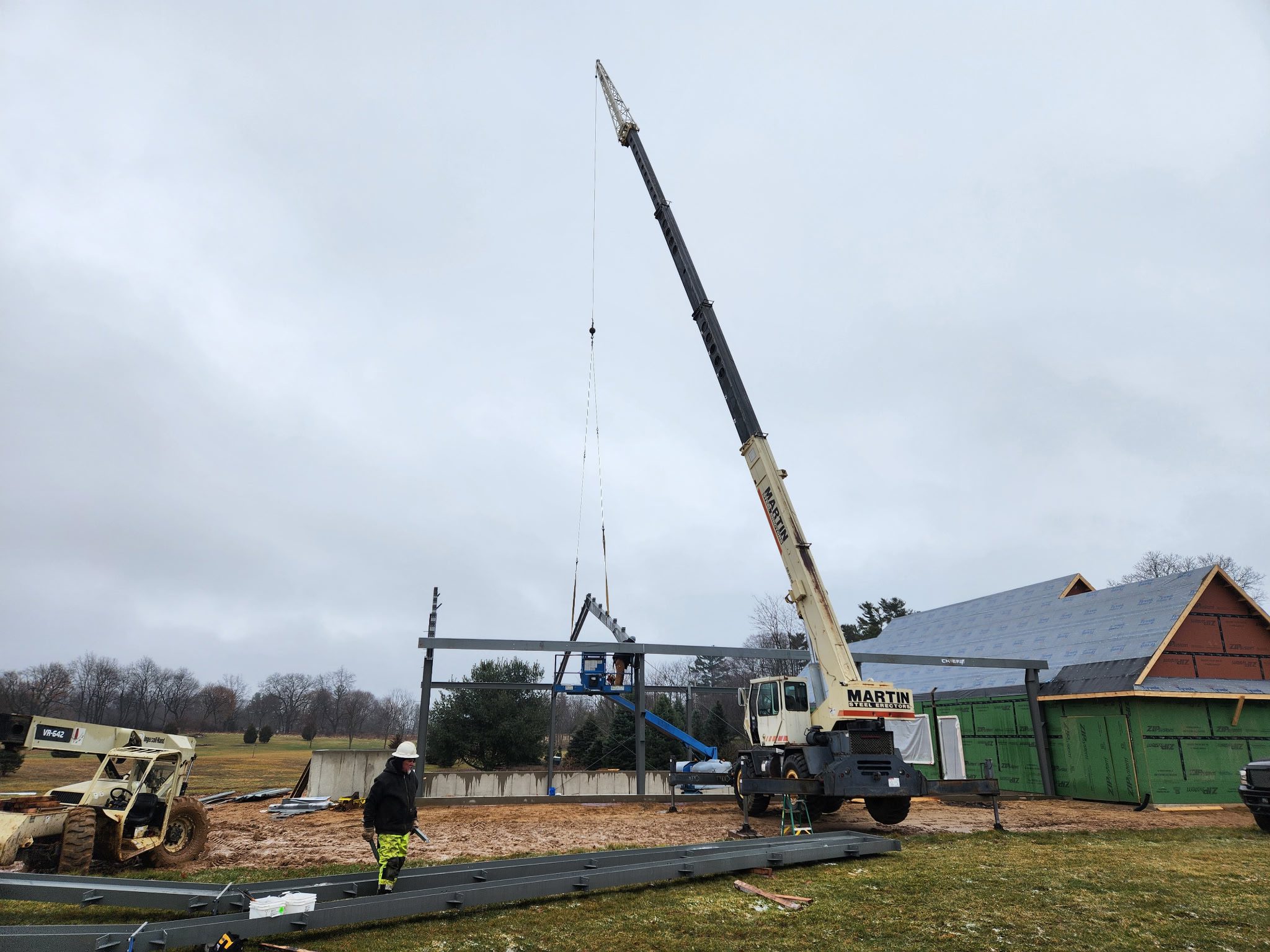 A crane lifting materials at a construction site with workers nearby.