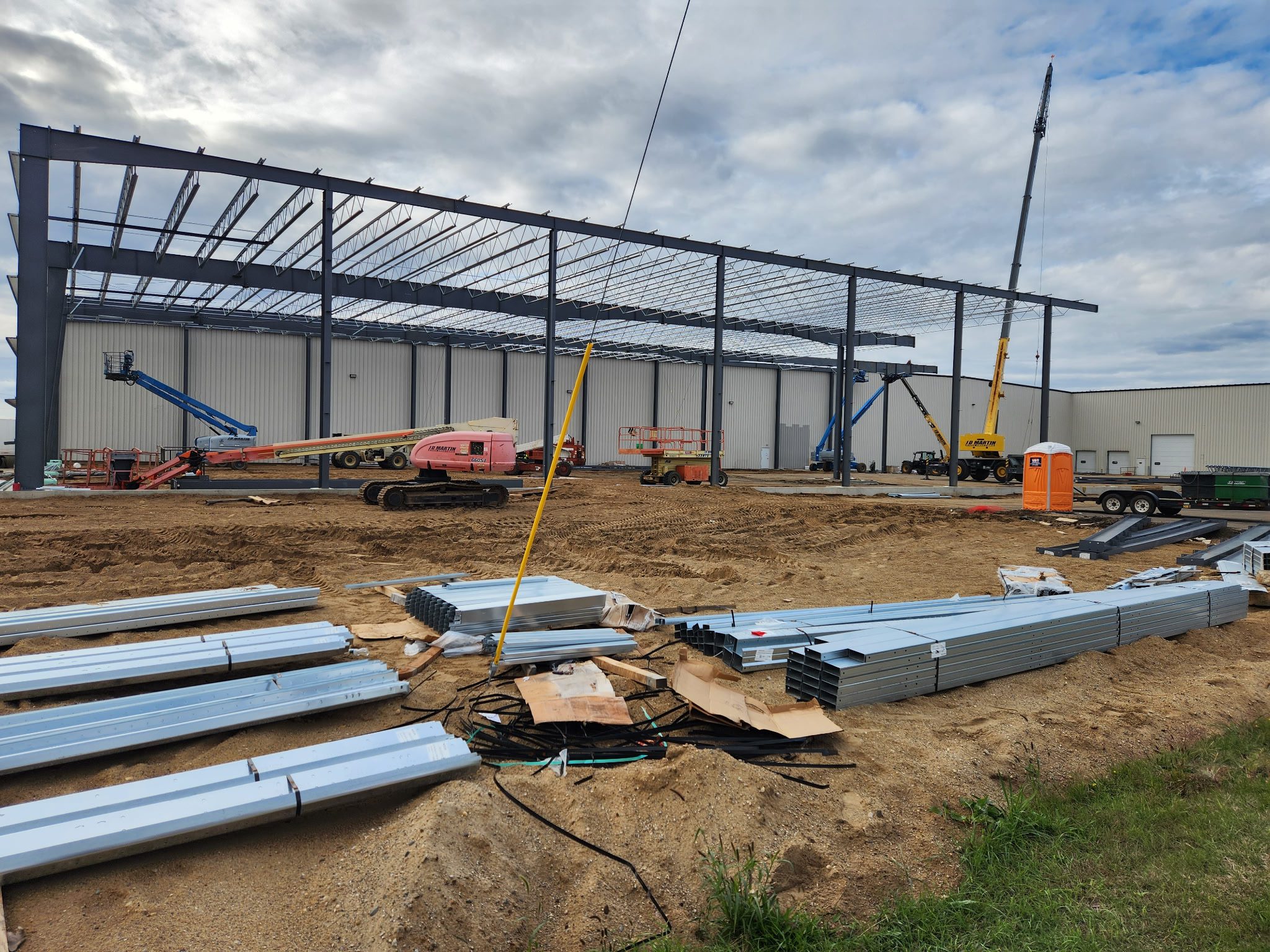 Steel framework construction in progress on a cloudy day.