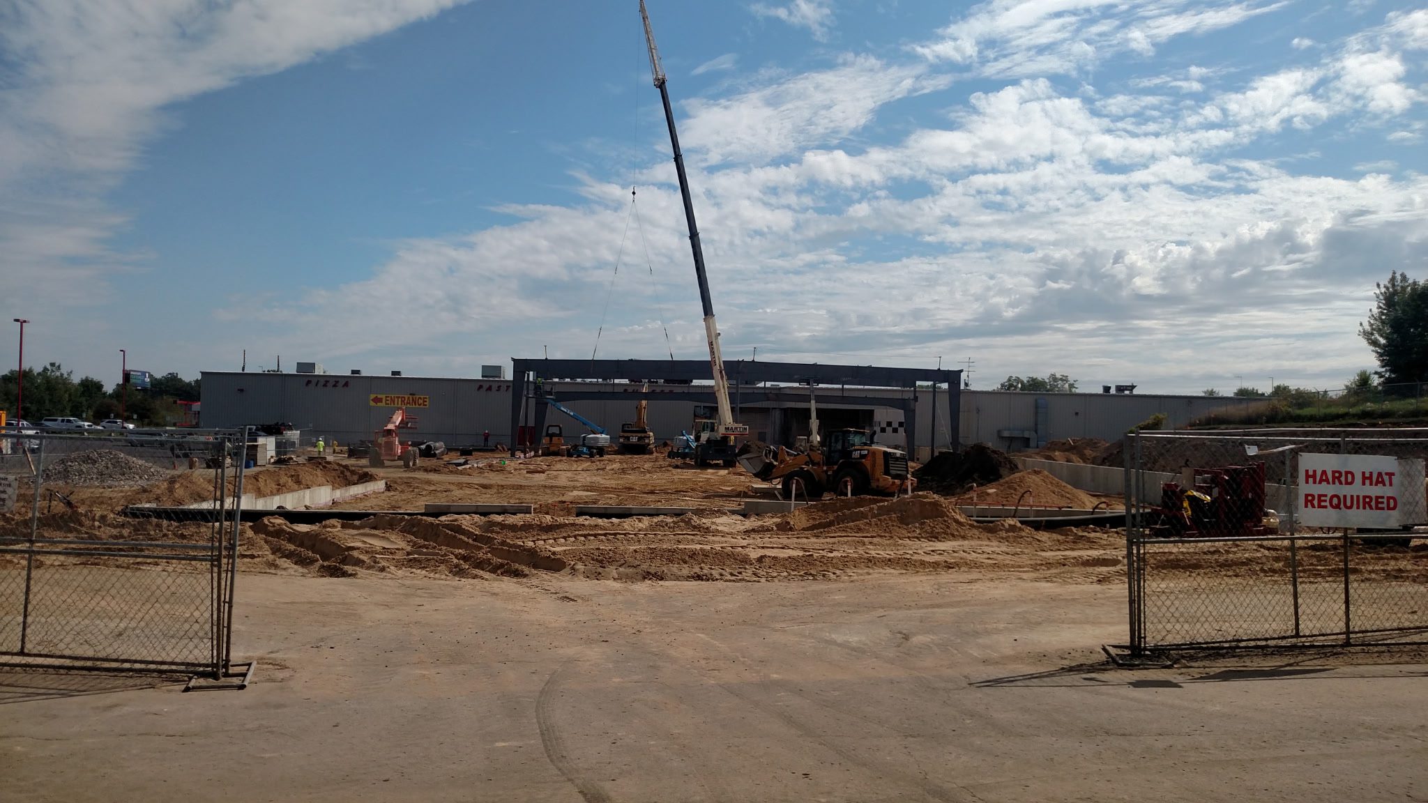 Construction site with workers and a crane assembling a building frame.