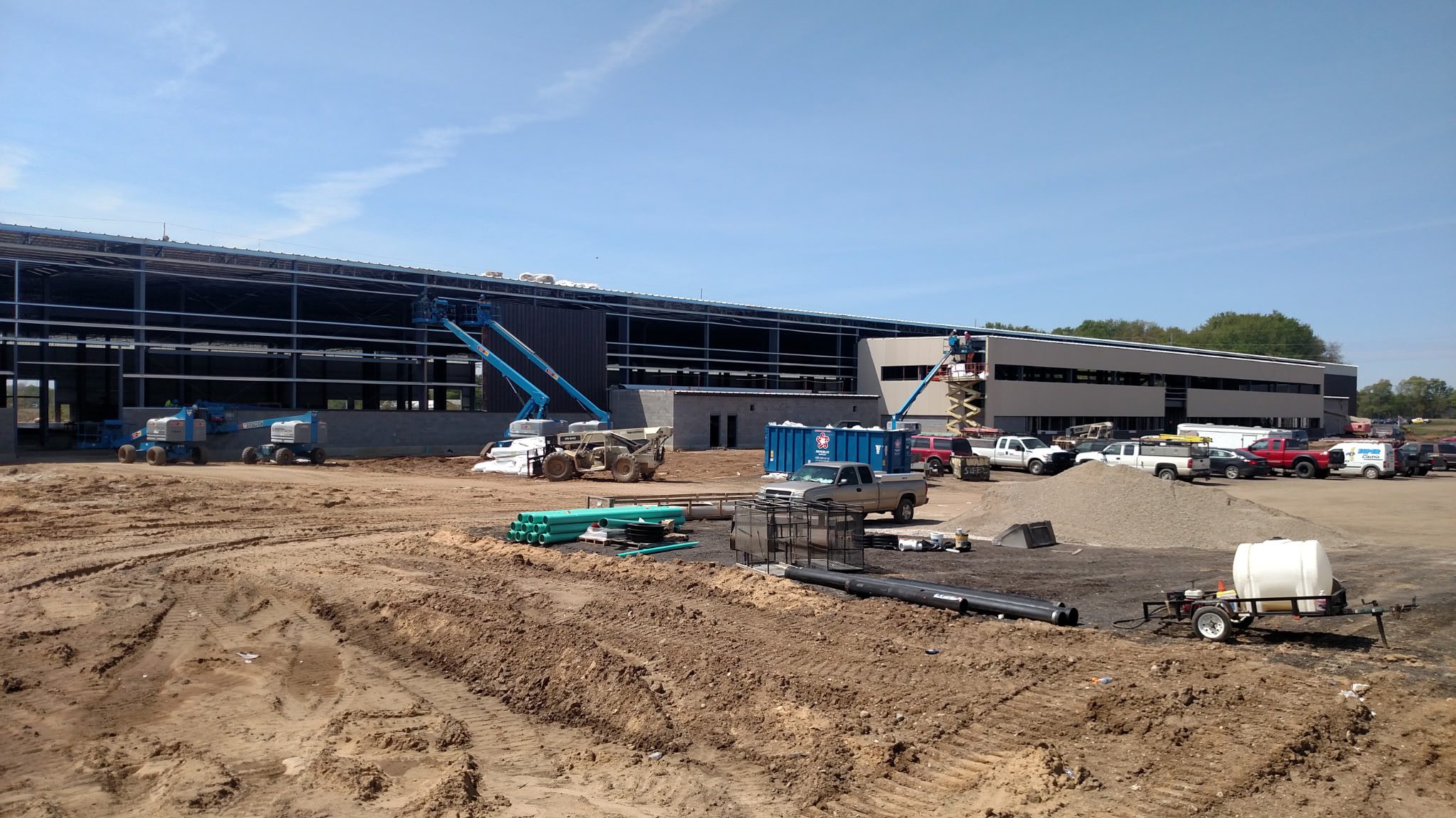 Construction site with heavy machinery and building framework under clear sky.