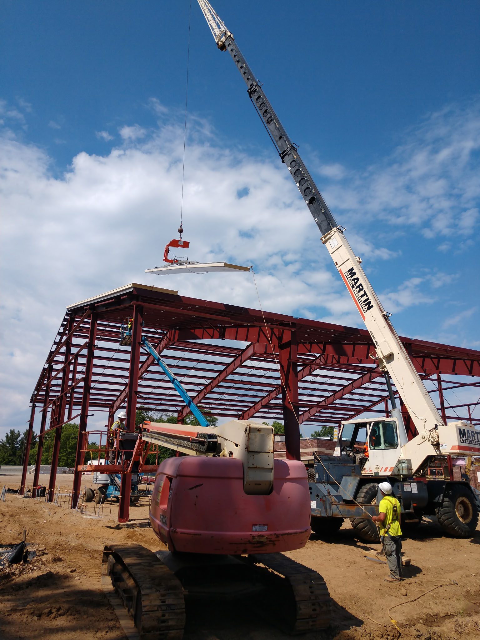 Construction site with crane lifting steel beam for building frame.