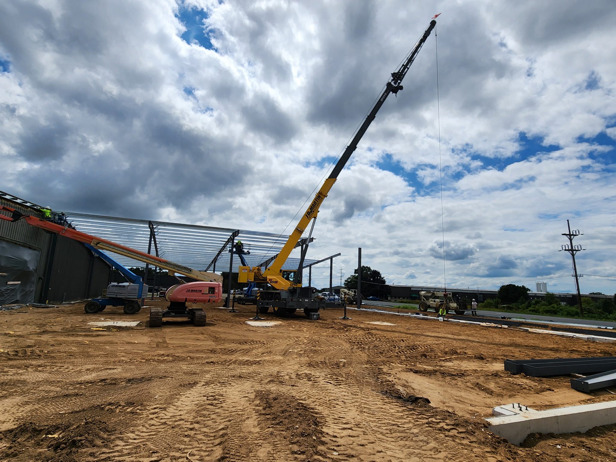 A crane lifting materials at a construction site under a partly cloudy sky.