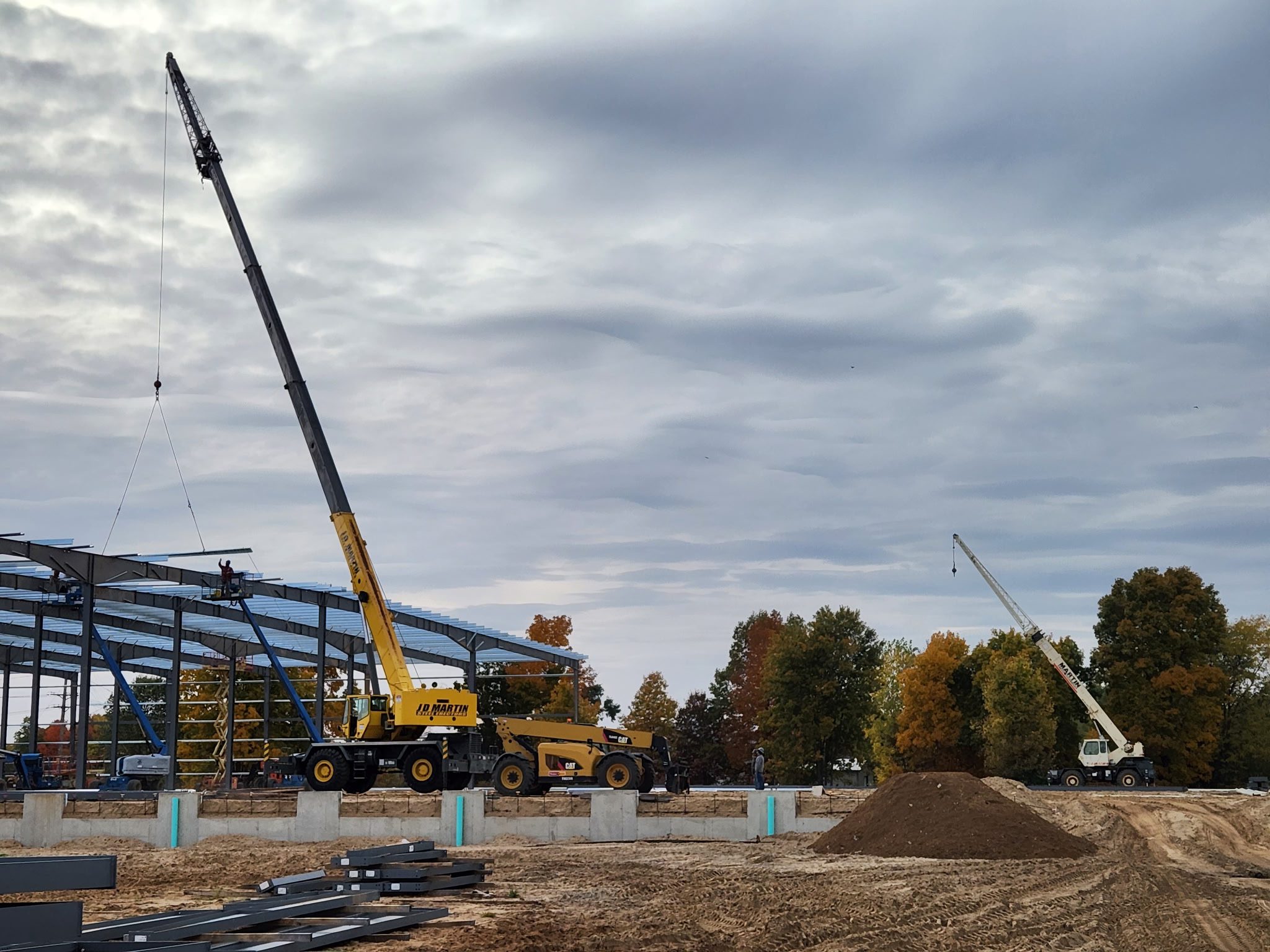 Construction site with cranes and building framework under a cloudy sky.