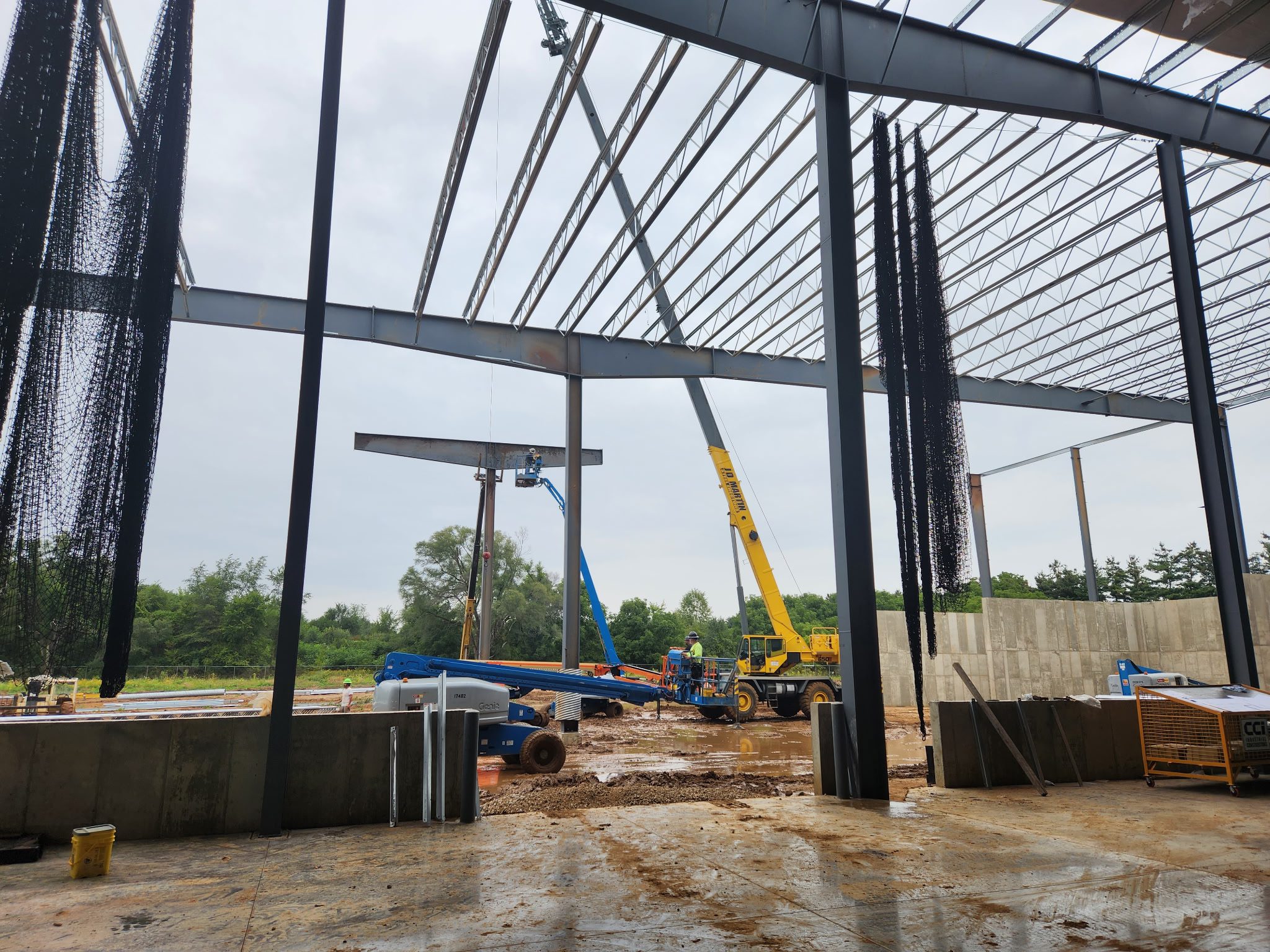 Construction site with steel framework and crane lifting materials.