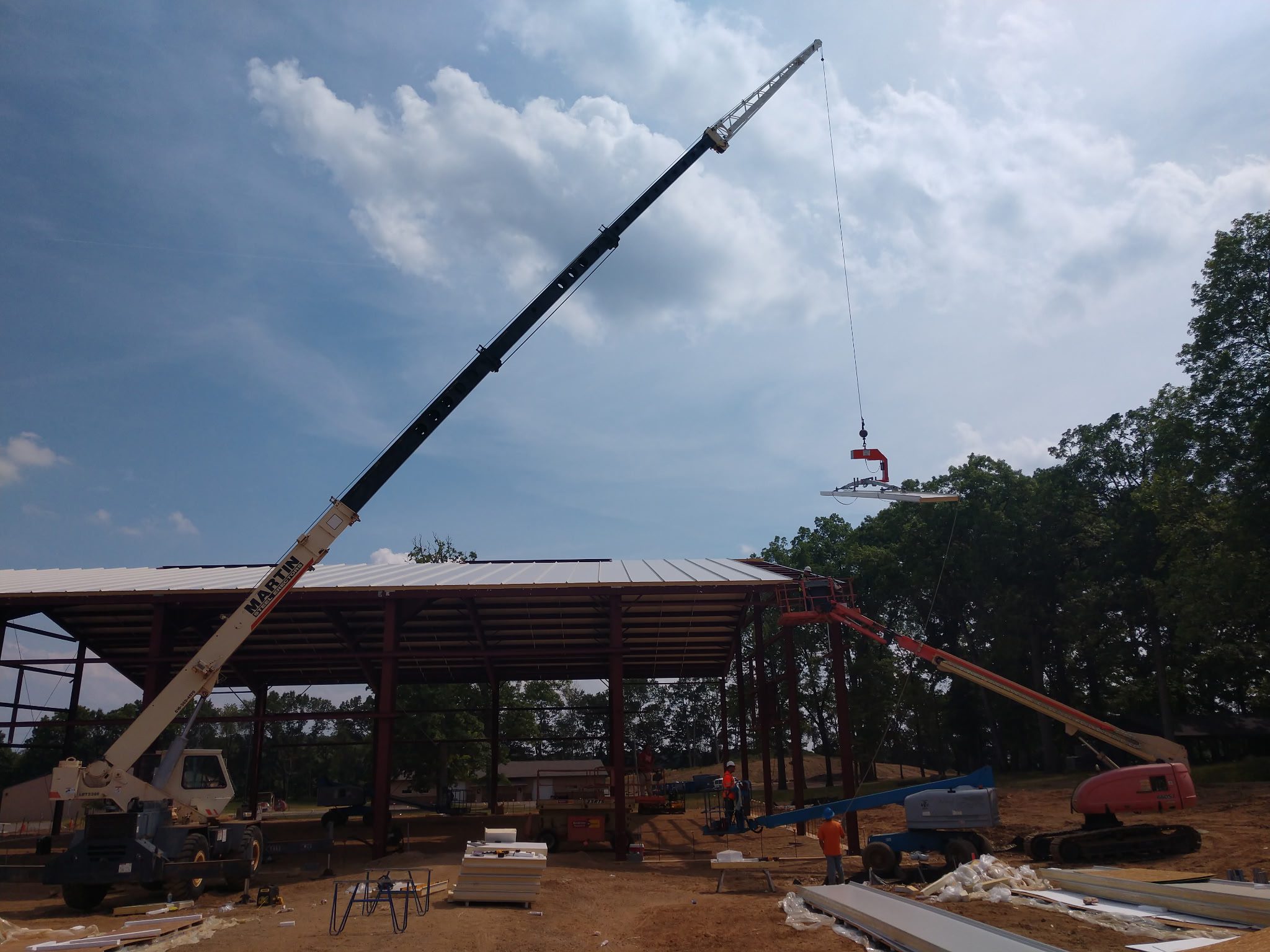Construction site with large crane lifting materials against a cloudy sky.
