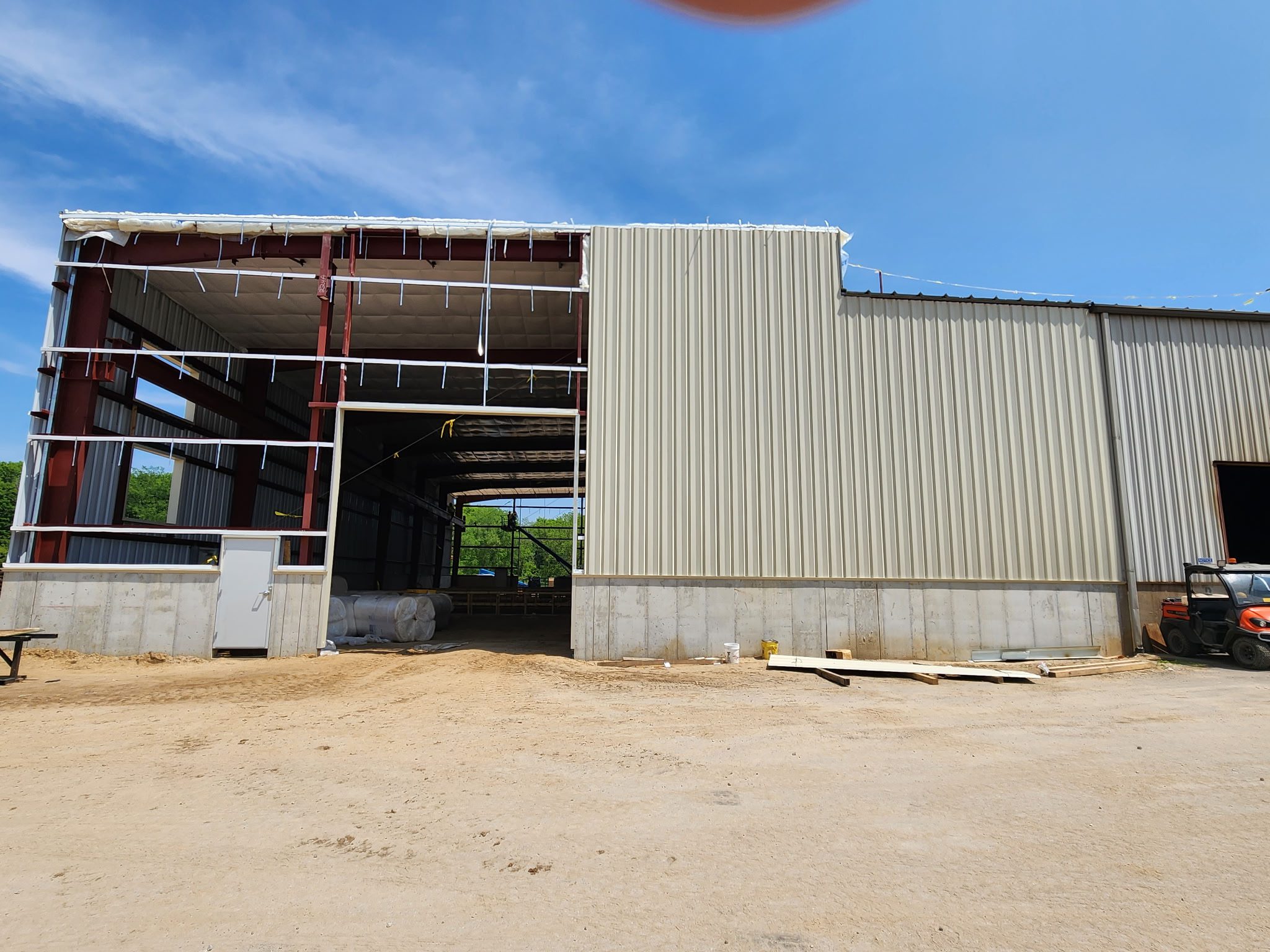 Exterior view of a large industrial warehouse with a partially open metal door.