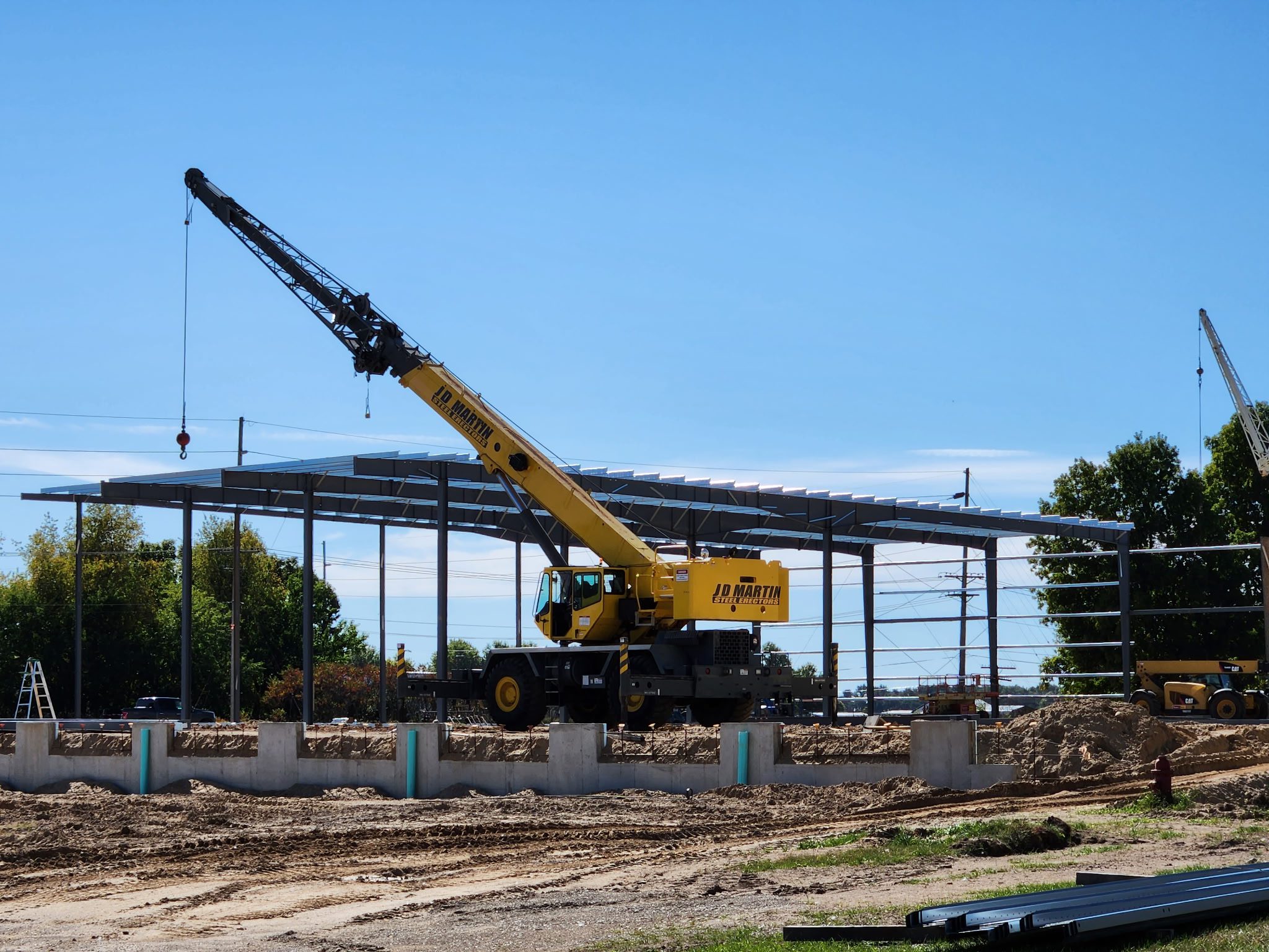 Yellow crane lifting materials at a construction site under clear blue sky.