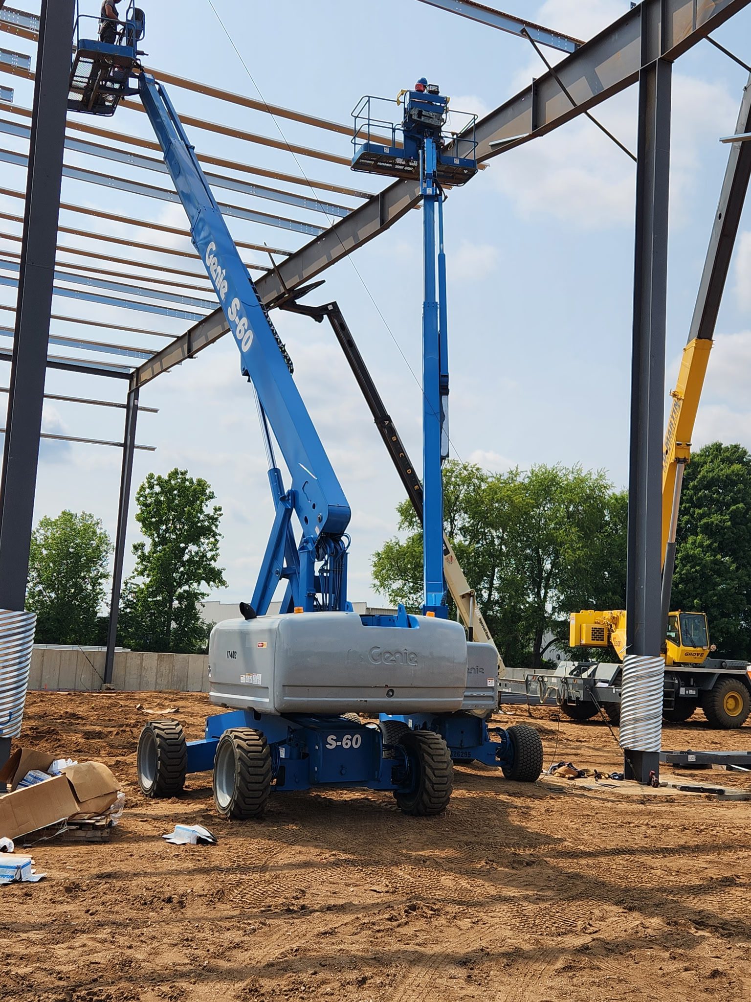 Construction site with a blue aerial lift and steel framework.