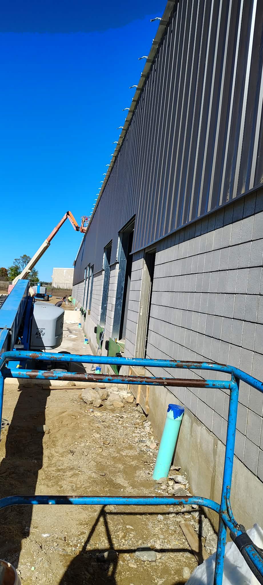 Construction site with building exterior and piping work underway.