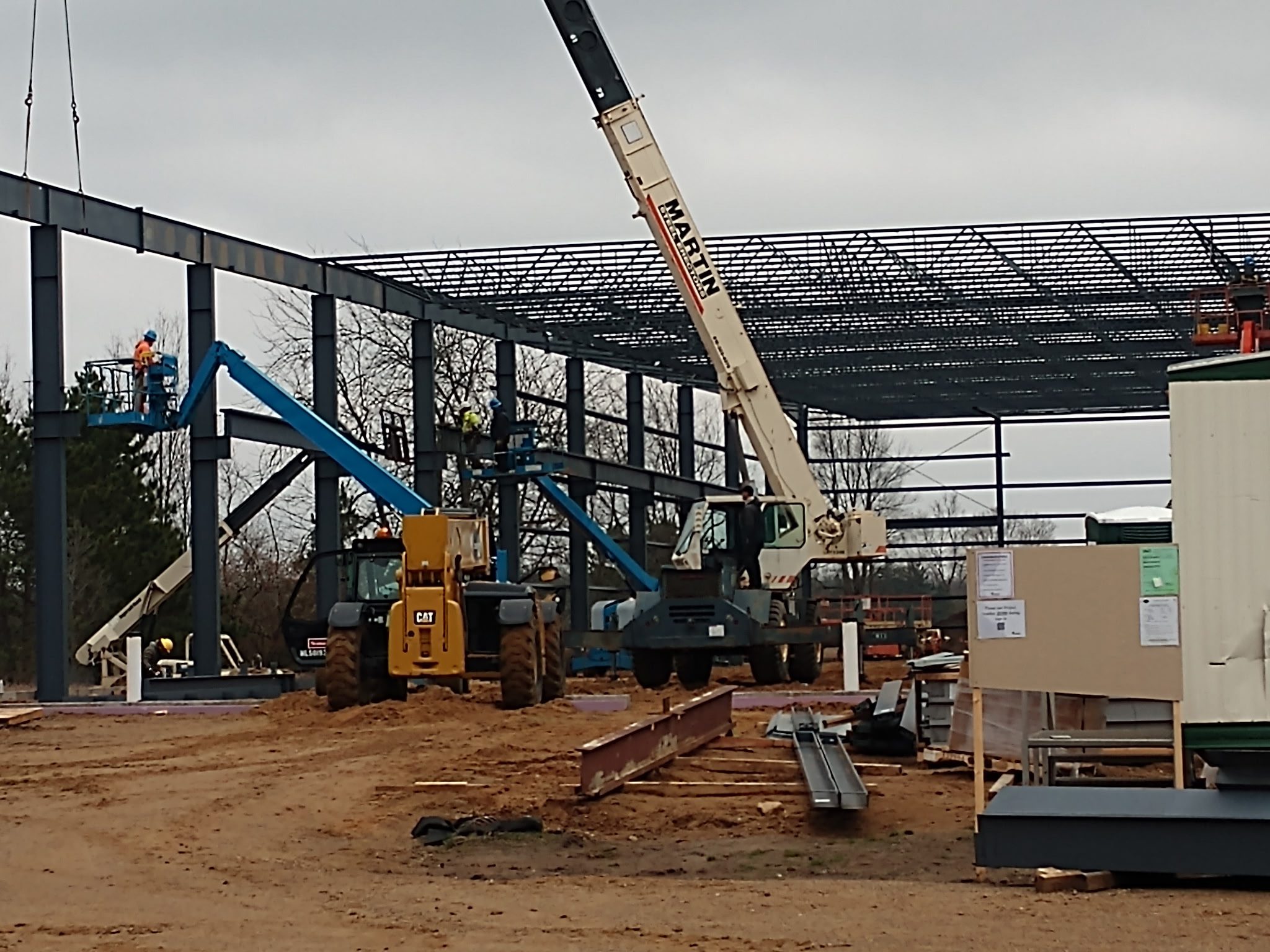 Construction site with cranes assembling steel framework.