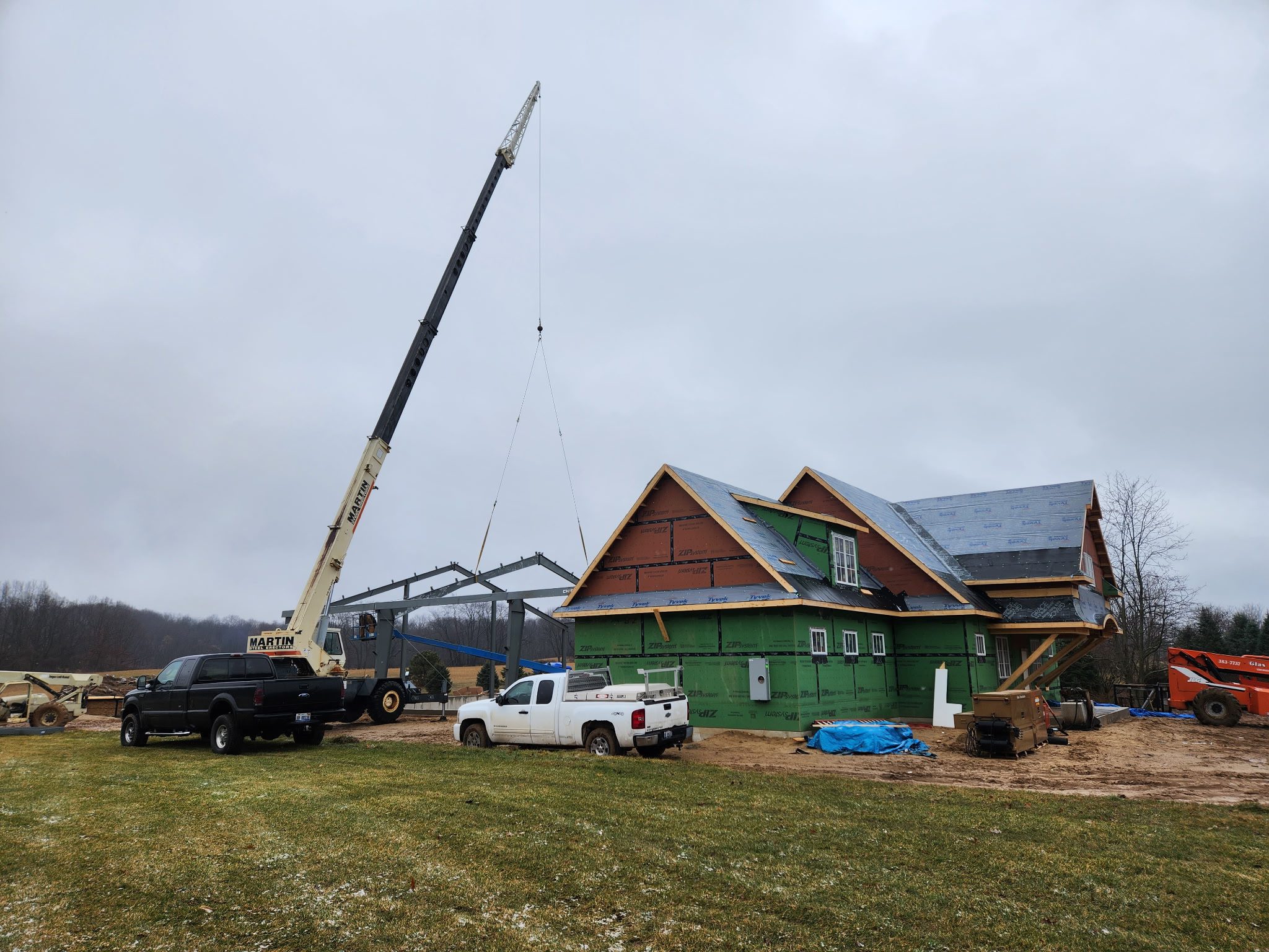 Construction of a large house with a crane lifting roof components.