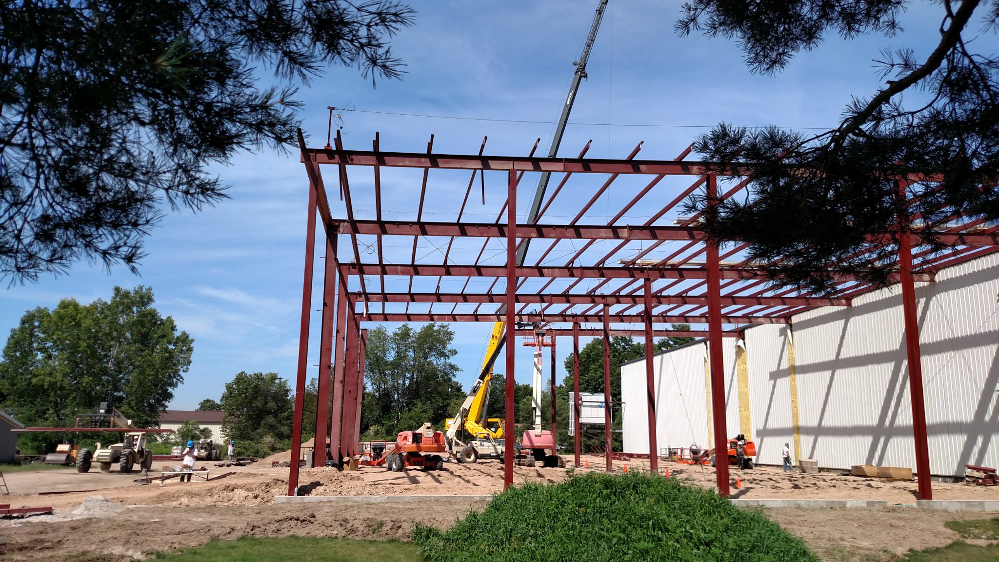 Steel framework of a building under construction with workers and a crane.
