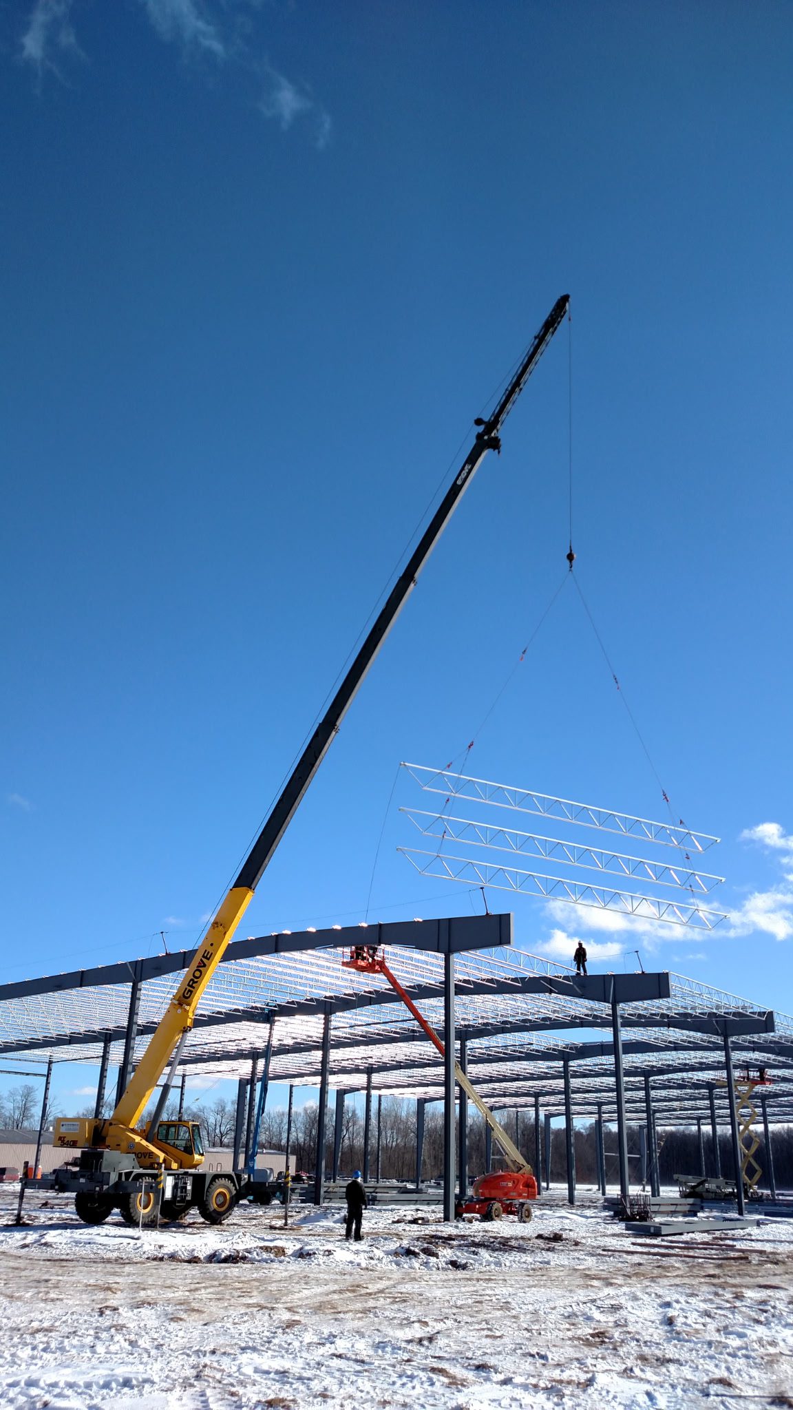 A crane lifting materials at a construction site with a clear blue sky.