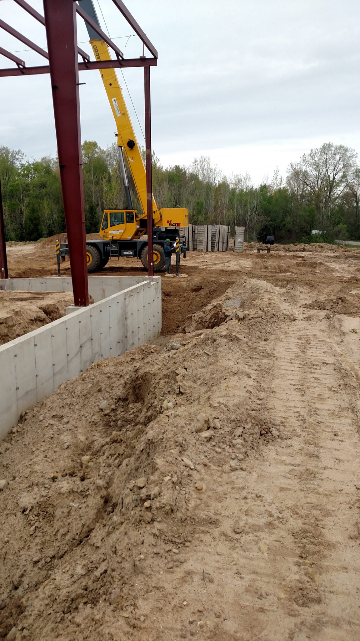 Construction site with foundation work and crane in progress.
