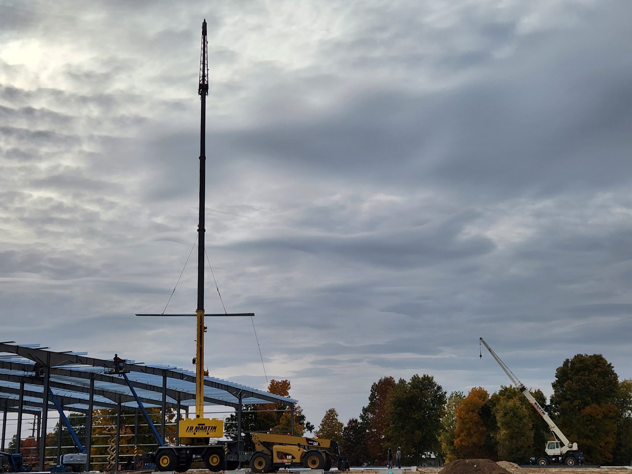 Construction site with cranes and equipment under a cloudy sky.
