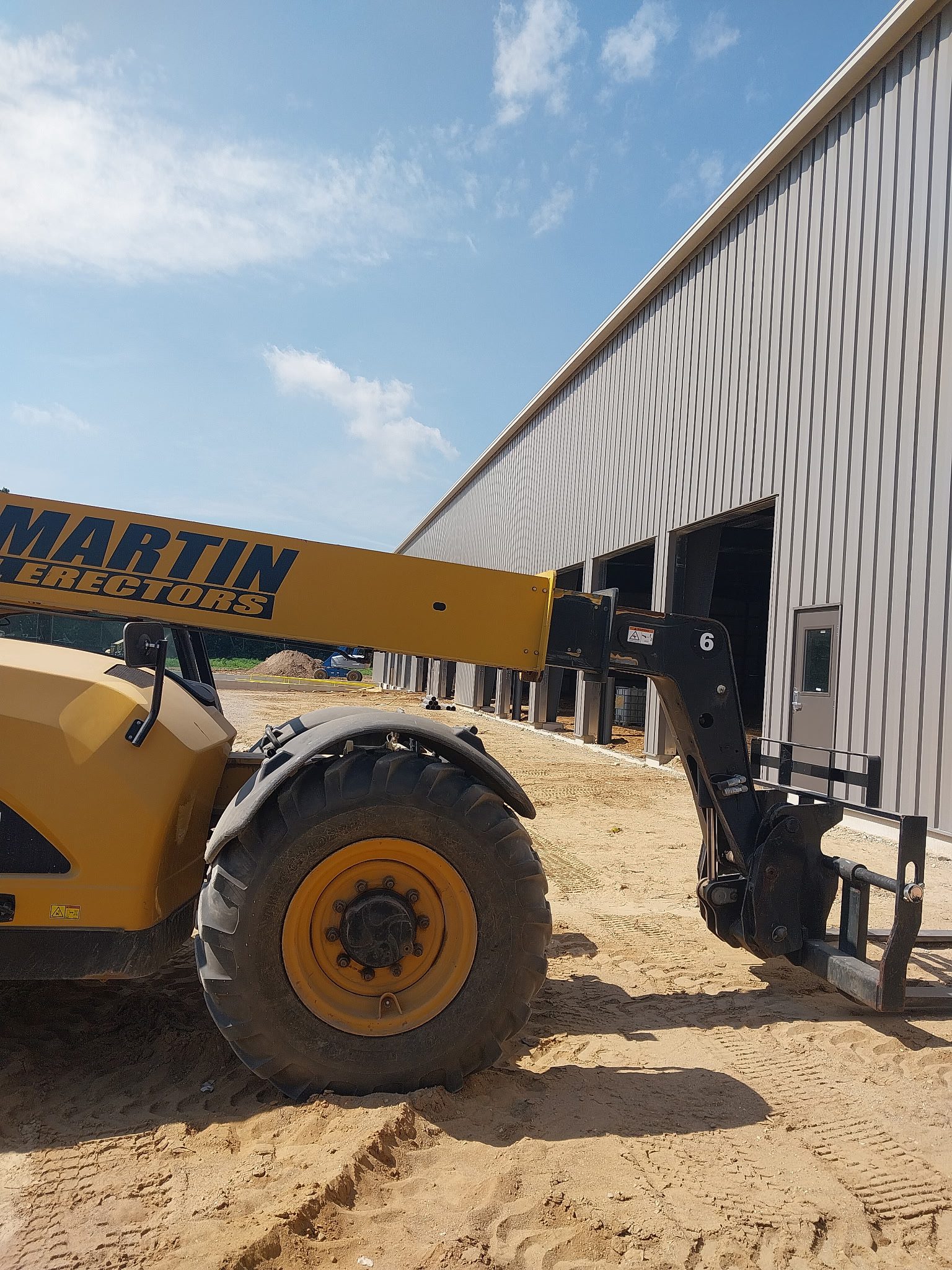 Yellow forklift operating outside a warehouse on a sunny day.