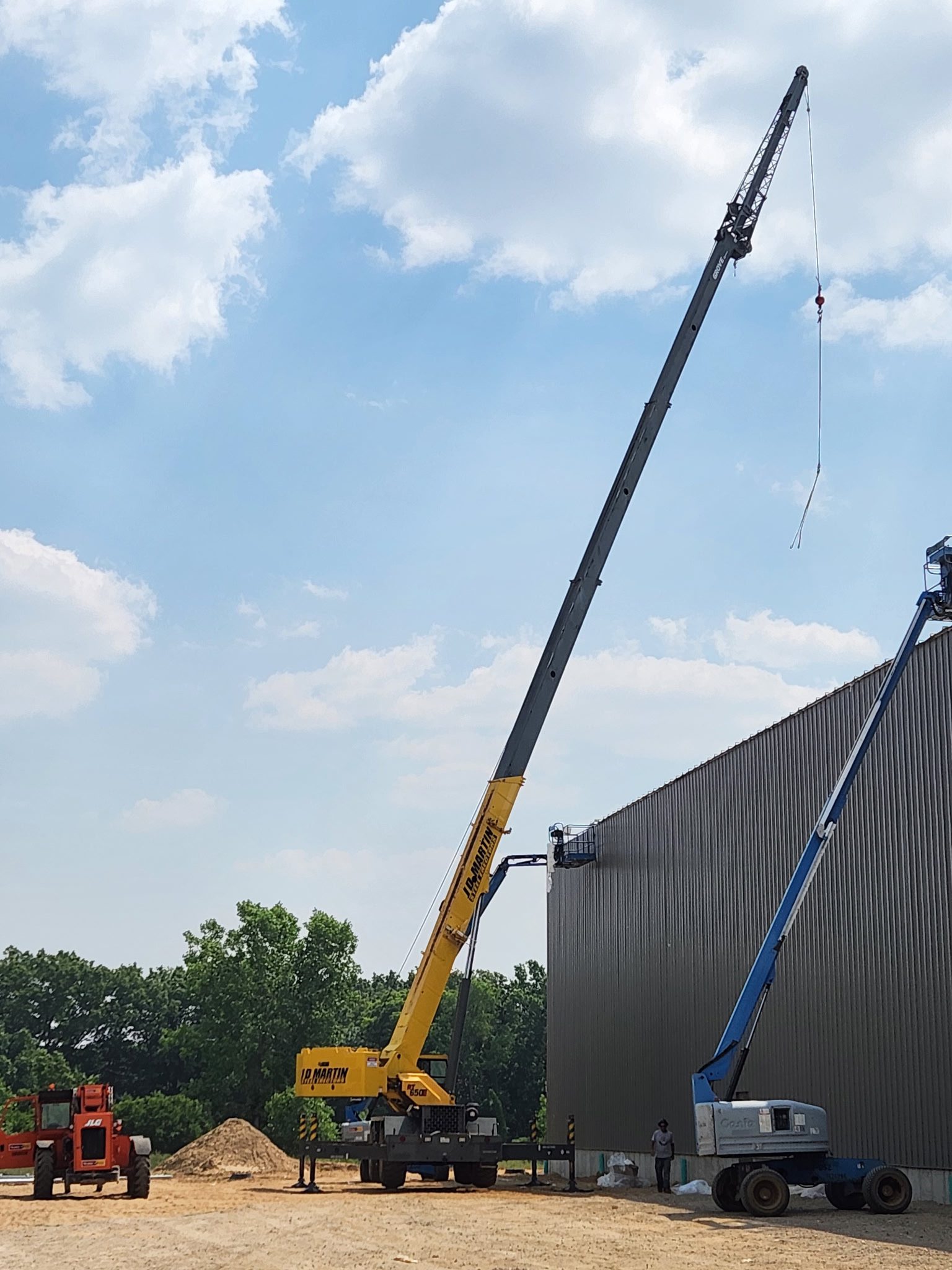 Yellow crane lifting a structure near a building on a sunny day.