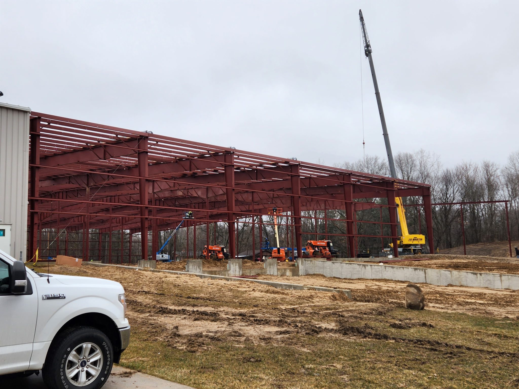 Steel framework of a large building under construction with a crane and workers.