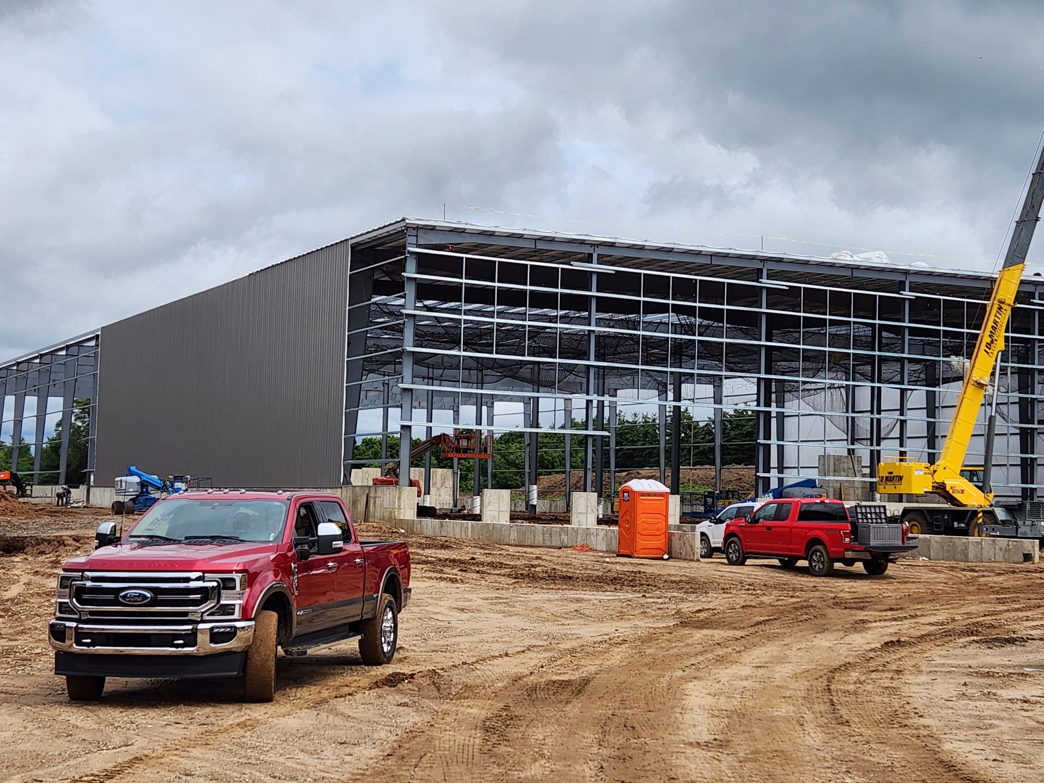 Construction site with a steel framework building and trucks.