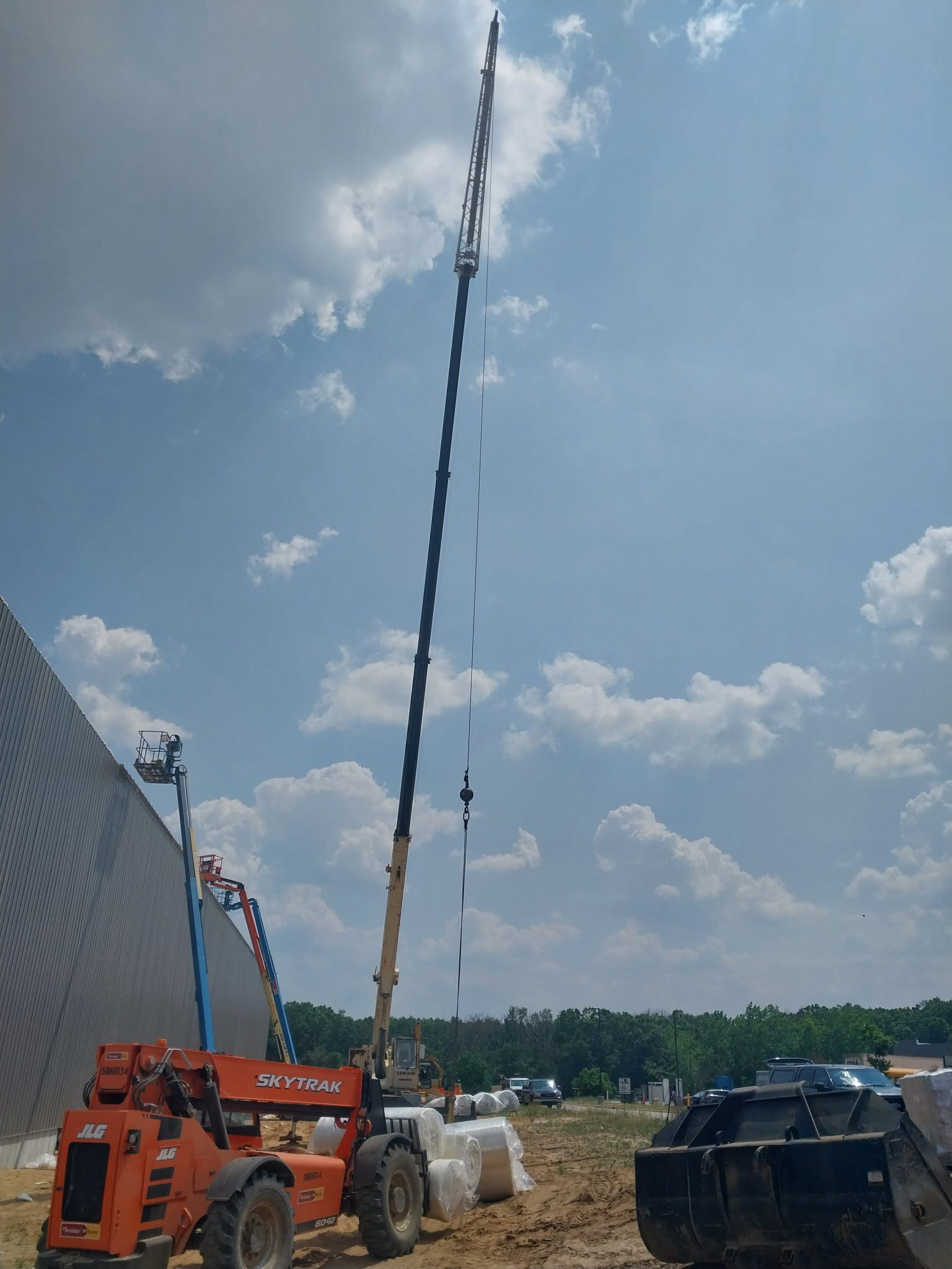 A crane lifting materials at a construction site under a cloudy sky.