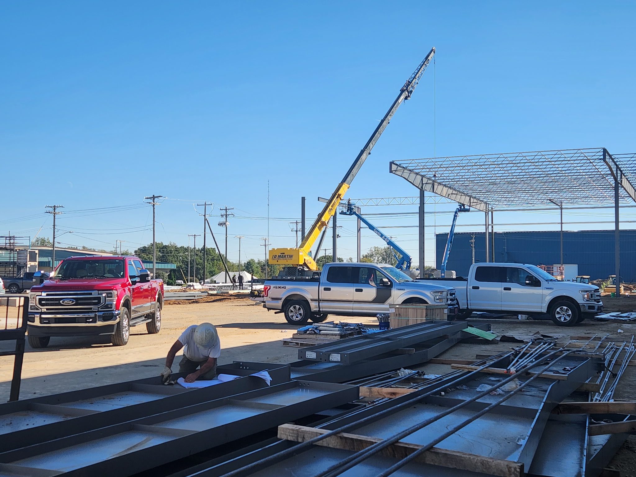 Construction site with cranes and vehicles under clear blue sky.