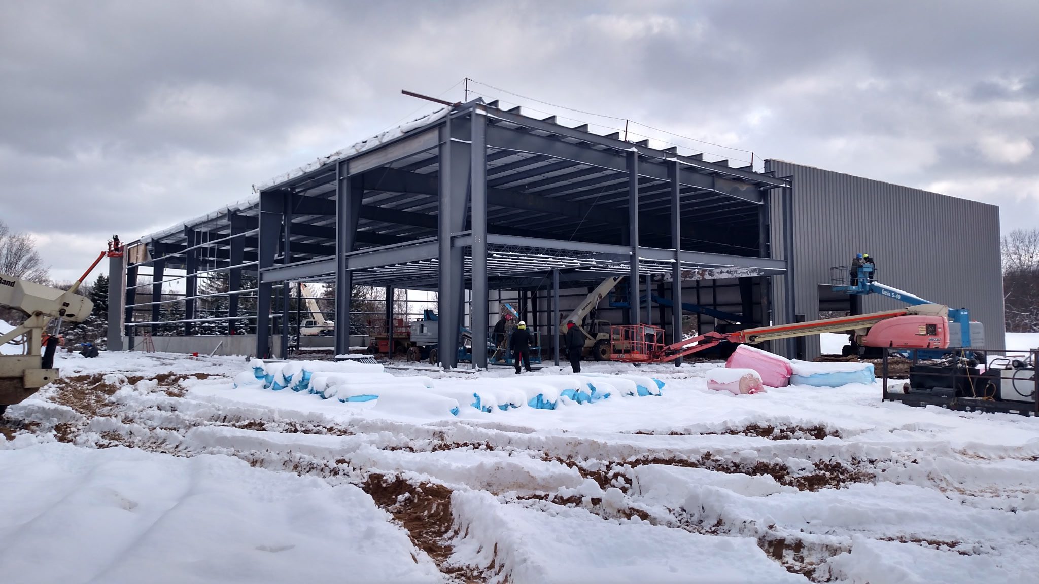 Steel frame structure under construction on a snowy site.
