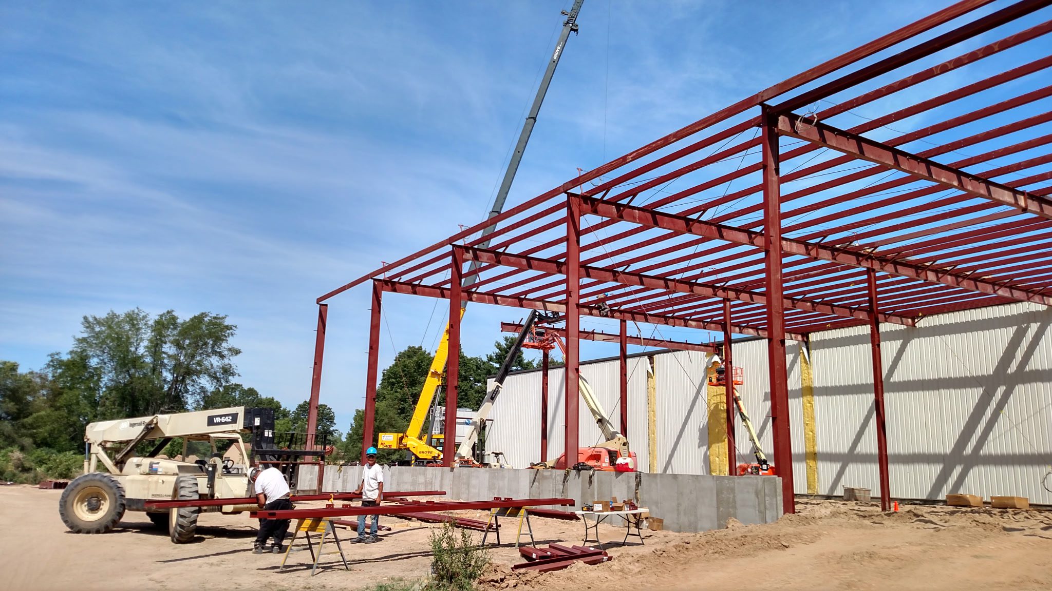 Steel frame construction in progress under a clear sky.