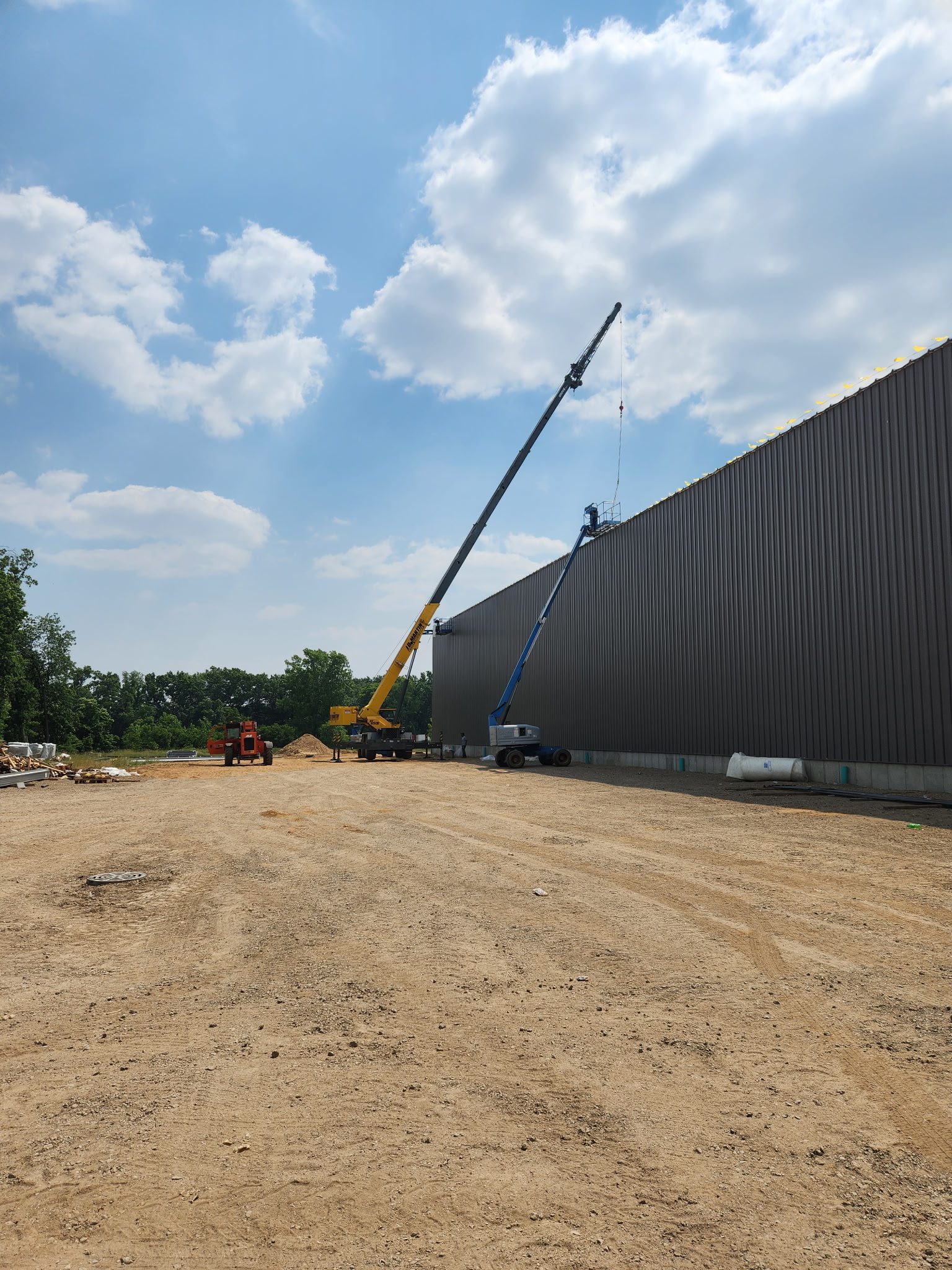 Crane lifting equipment beside a large building under construction on a clear day.