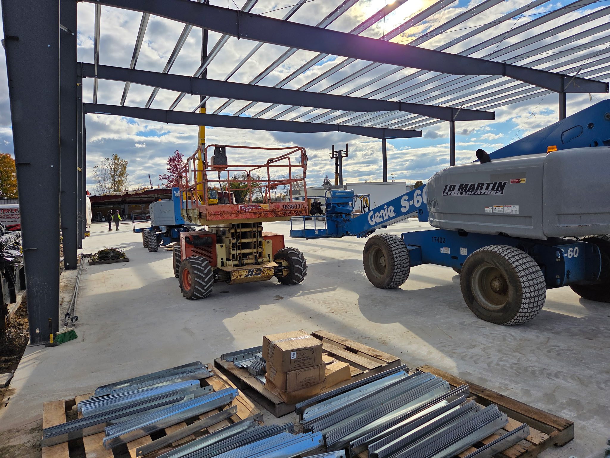 Construction site with heavy machinery under a partially covered roof.