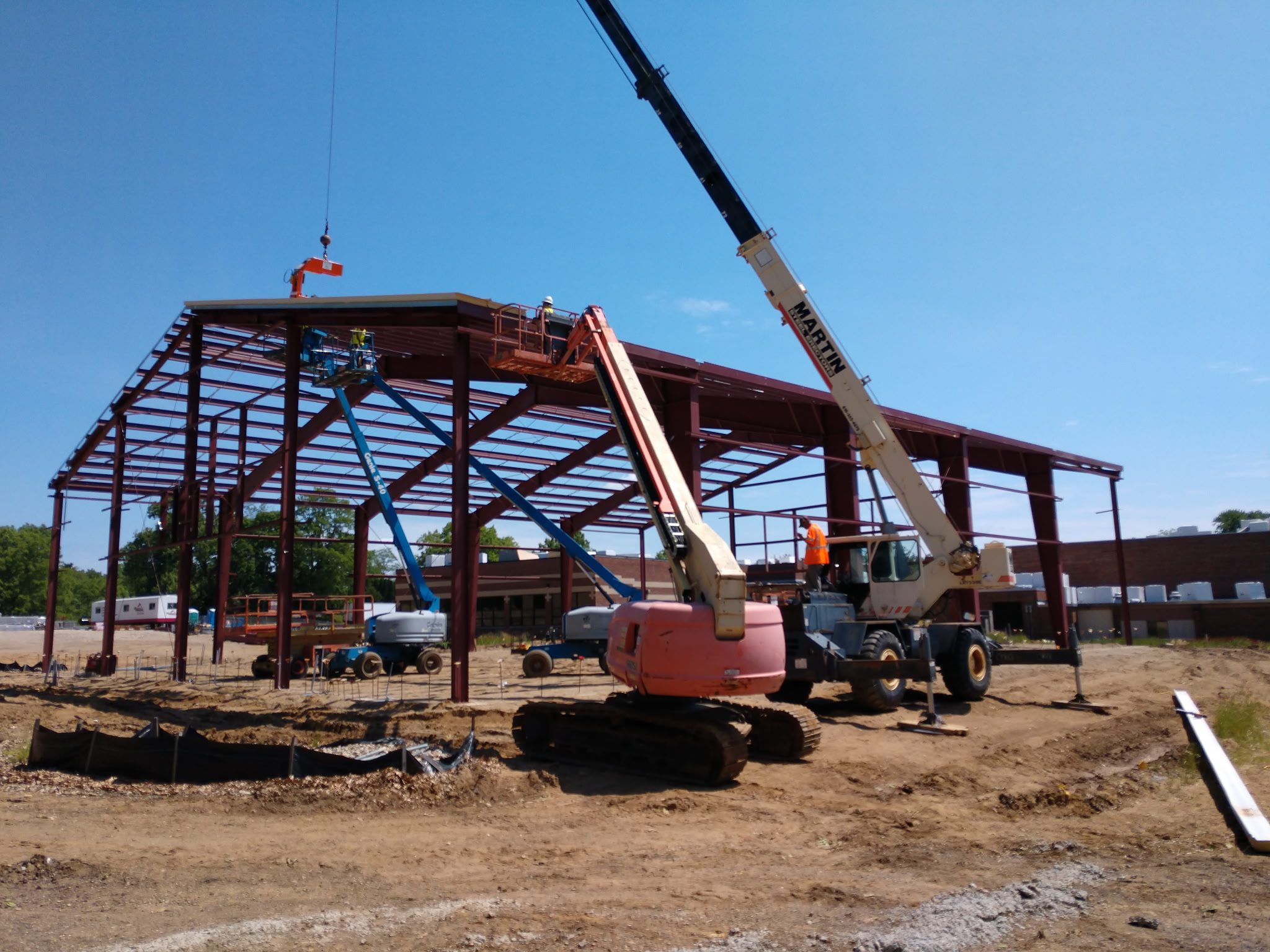 Construction site with steel framework and crane lifting materials.