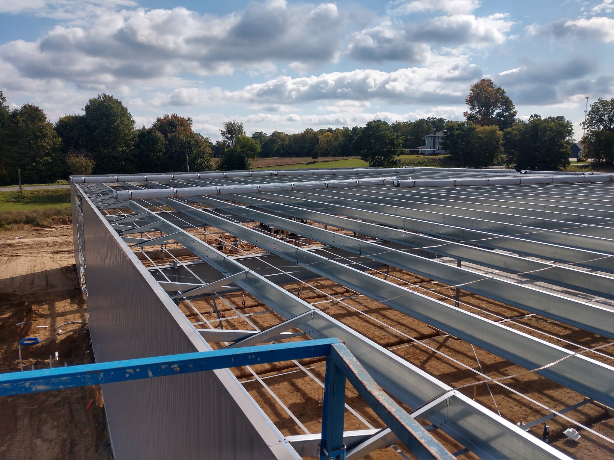 Steel framework being installed on a rooftop under a cloudy sky.