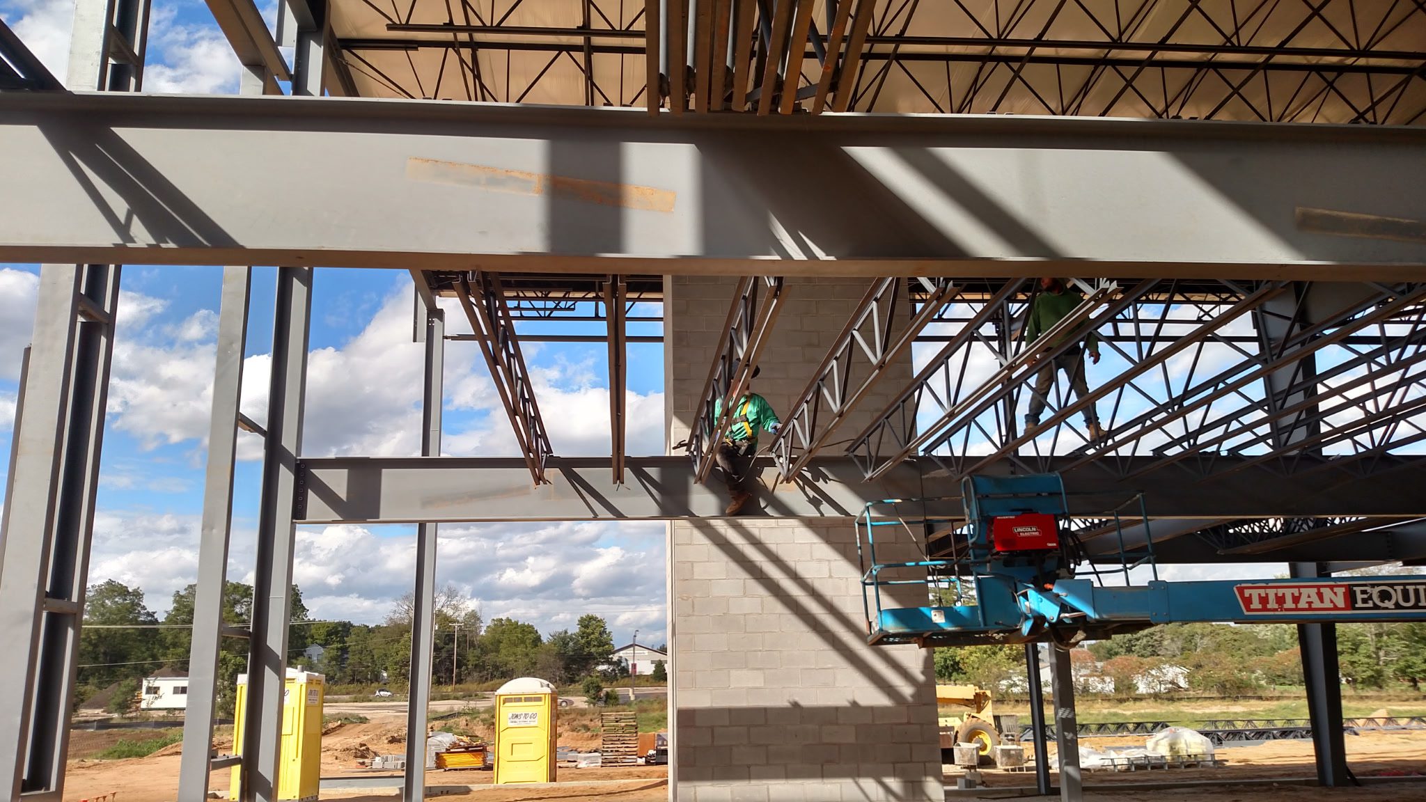 Construction workers install a large steel beam on a building frame.