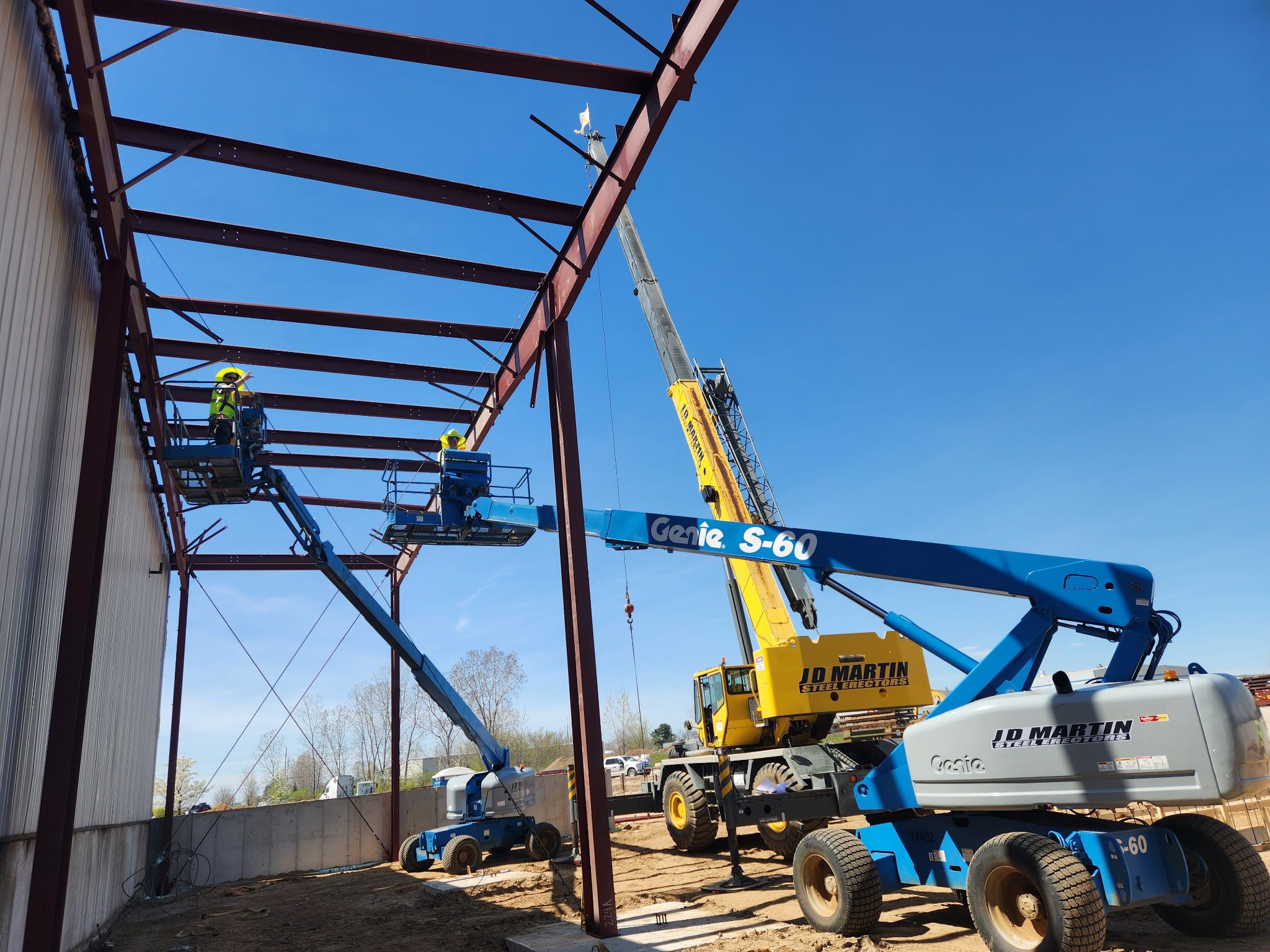 Construction site with cranes and steel framework under a clear sky.