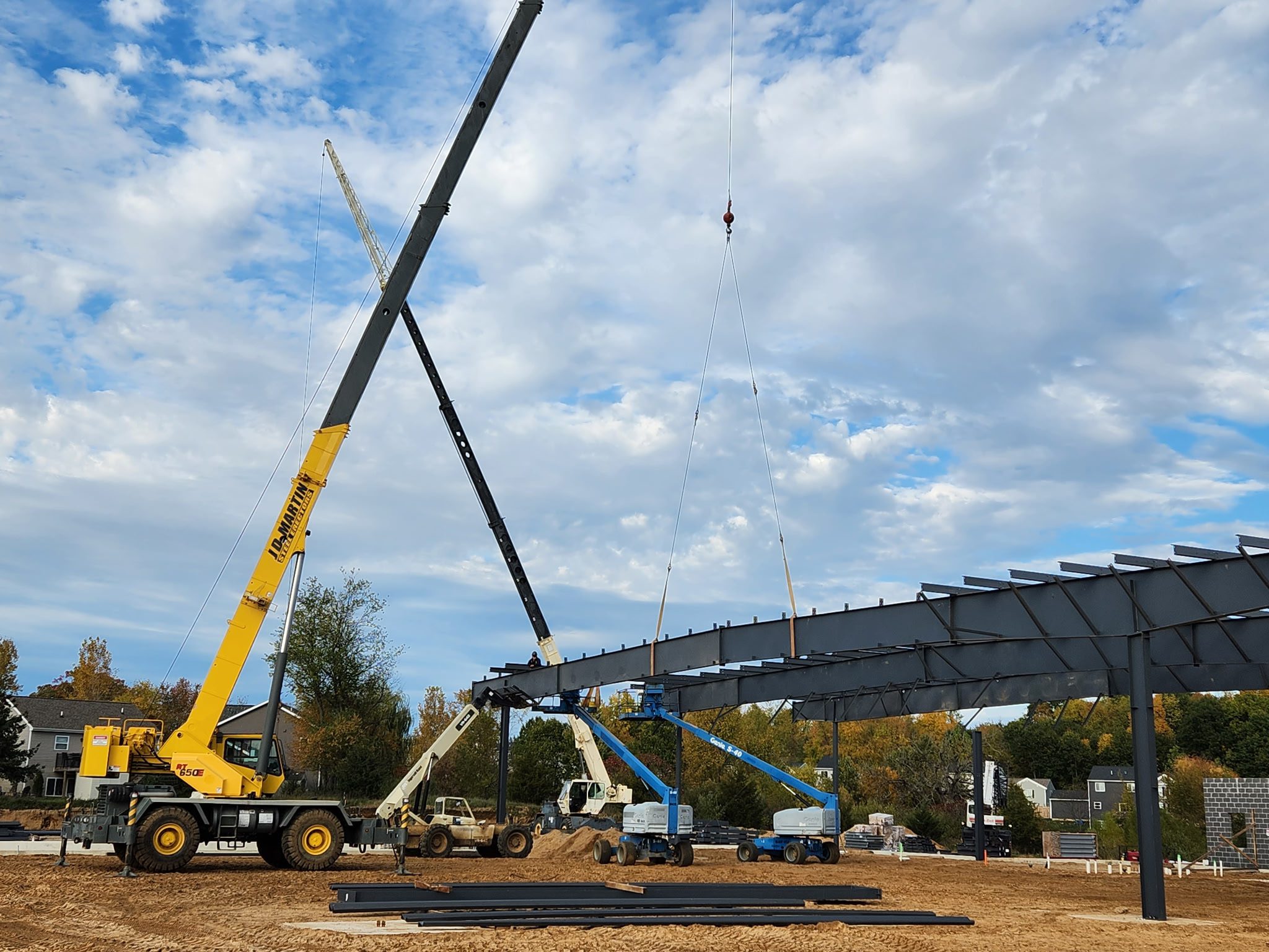 Construction cranes lifting steel beams on a building site.