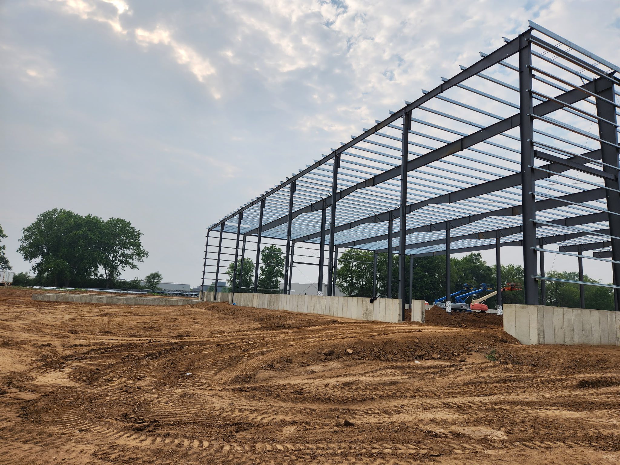 Steel framework of a large building under construction on a cloudy day.