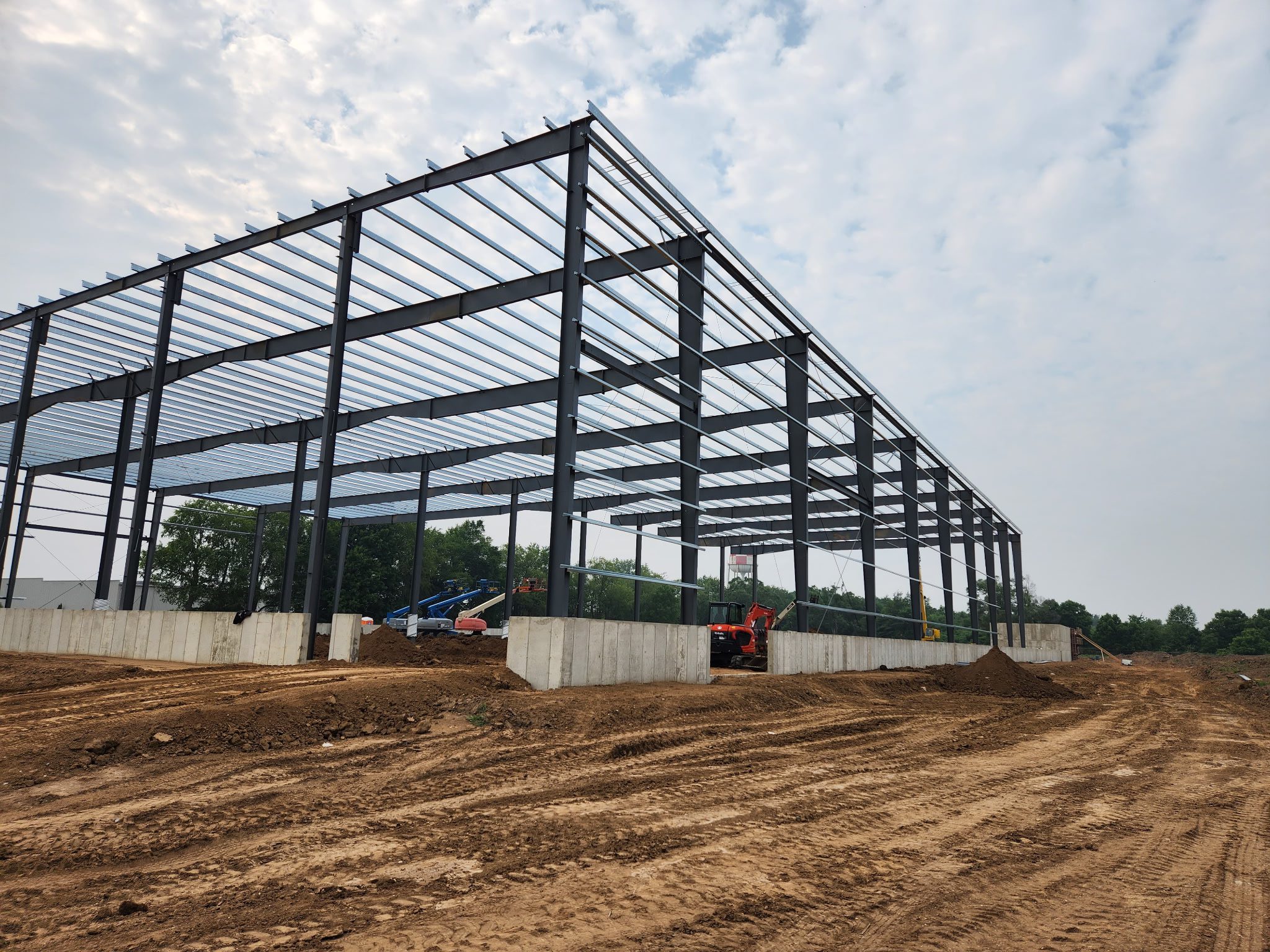 Steel framework of a large building under construction on a cloudy day.