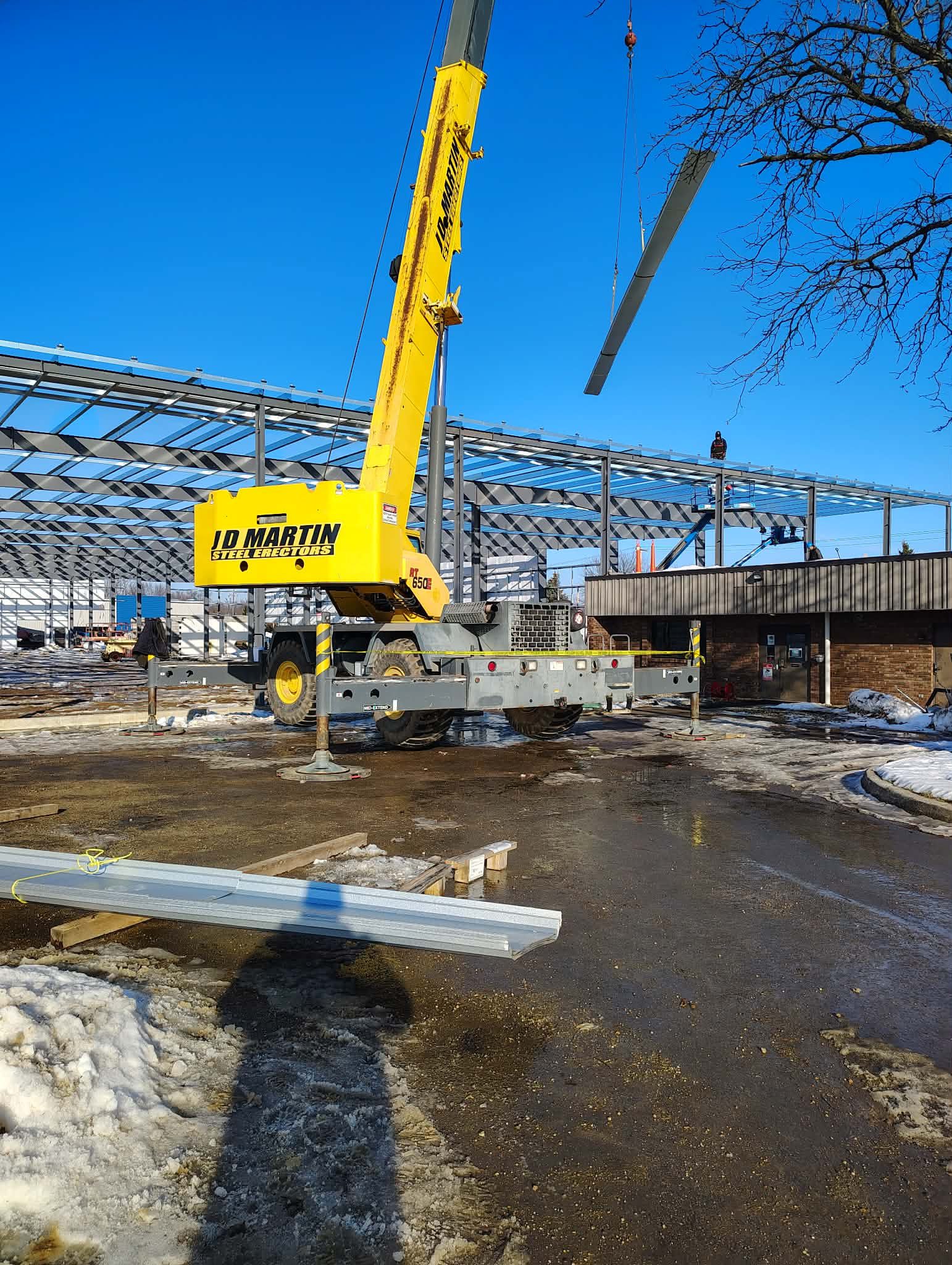 A yellow crane operating at a construction site with steel framework.