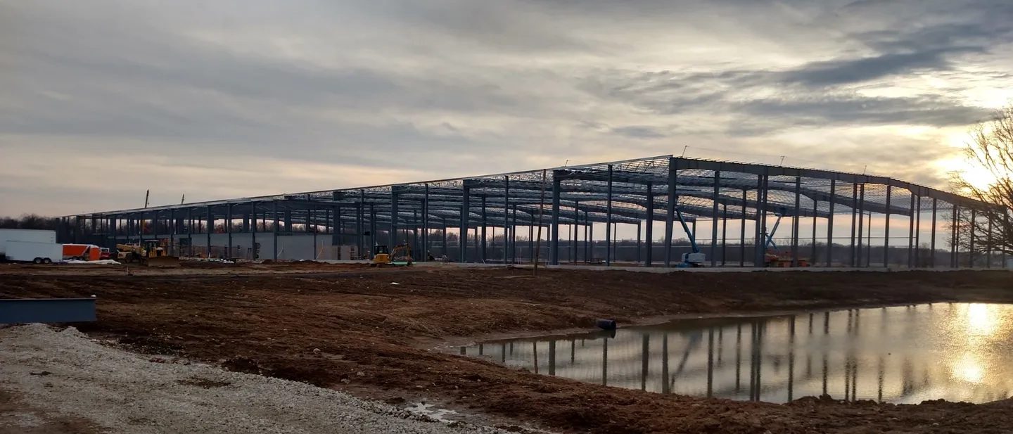 Steel framework of a large building under construction at dusk.