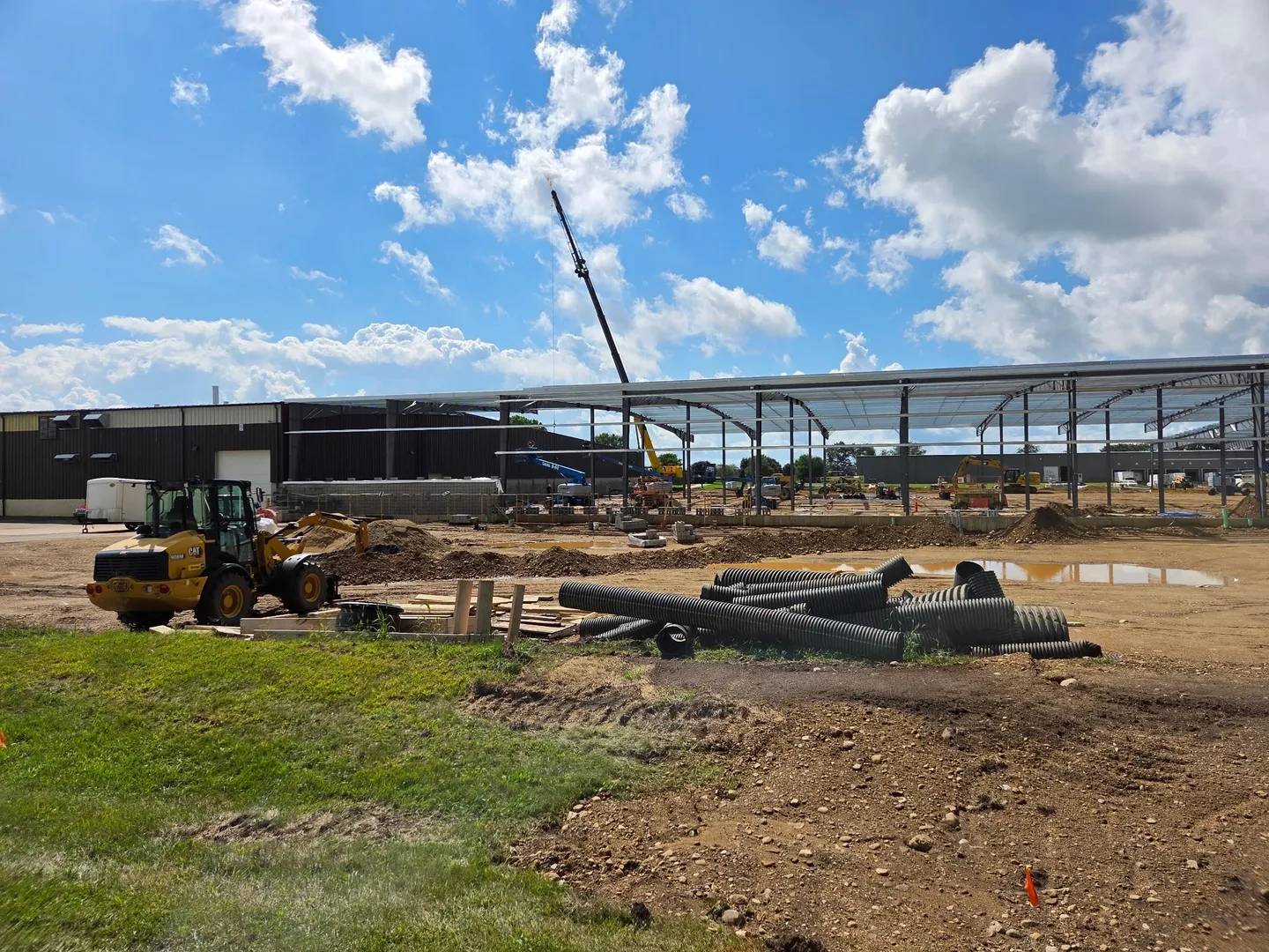 Construction site with machinery and steel beams under a blue sky.