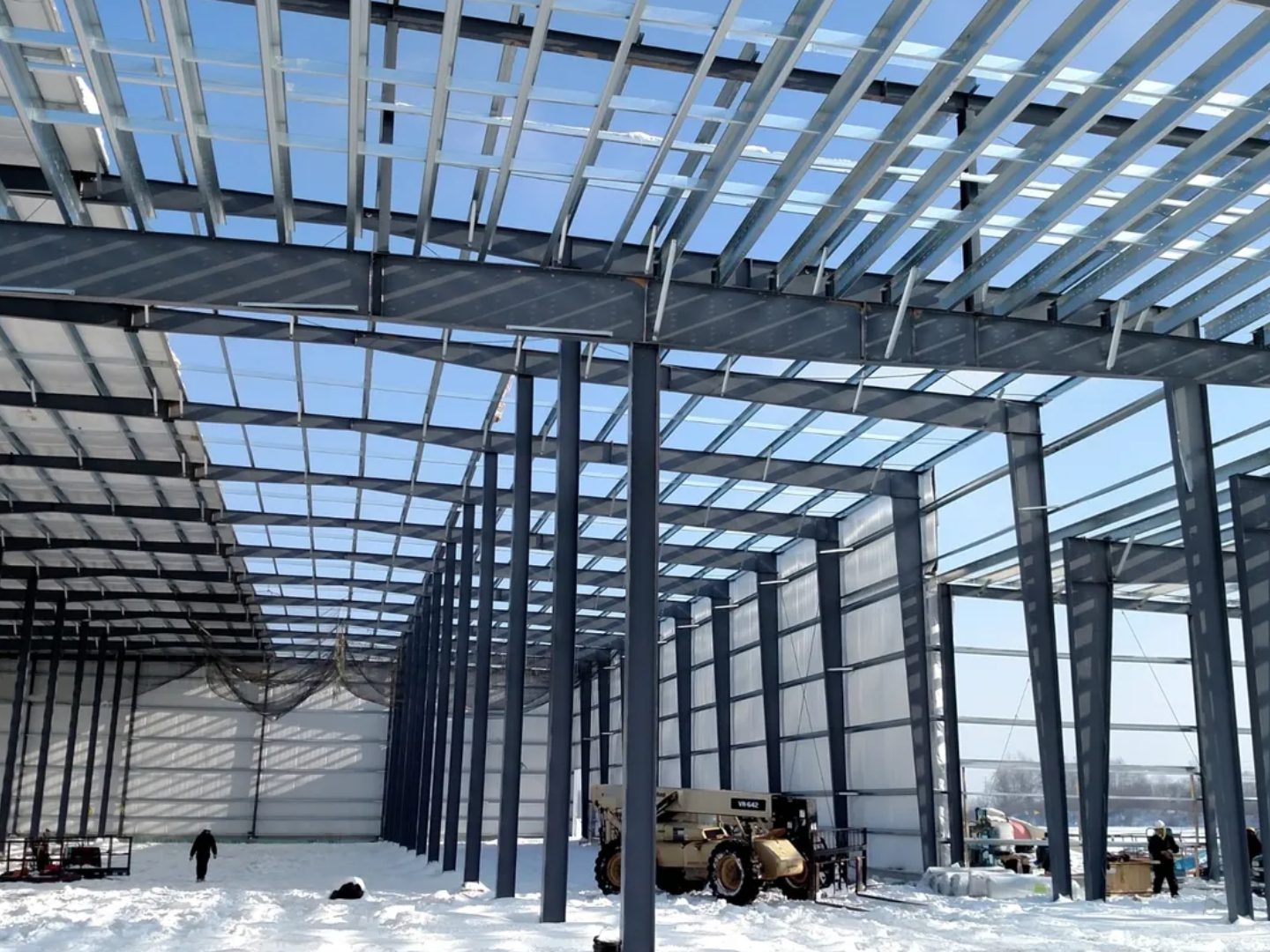 Steel framework of a building under construction in a snowy environment.
